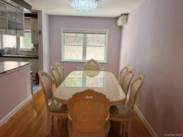 Dining area featuring wood-finish flooring, a contemporary chandelier, and a window providing natural light Dining area featuring wood-finish flooring, a contemporary chandelier, and a window providing natural light