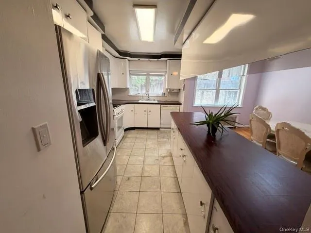 Kitchen featuring stainless steel appliances, white cabinetry, a tiled floor, and a dark wood-finish countertop on the island Kitchen featuring stainless steel appliances, white cabinetry, a tiled floor, and a dark wood-finish countertop on the island