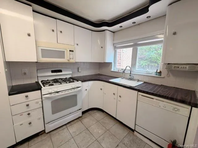 Kitchen featuring white cabinetry and appliances, wood-finish countertops, tiled backsplash, and recessed lighting Kitchen featuring white cabinetry and appliances, wood-finish countertops, tiled backsplash, and recessed lighting
