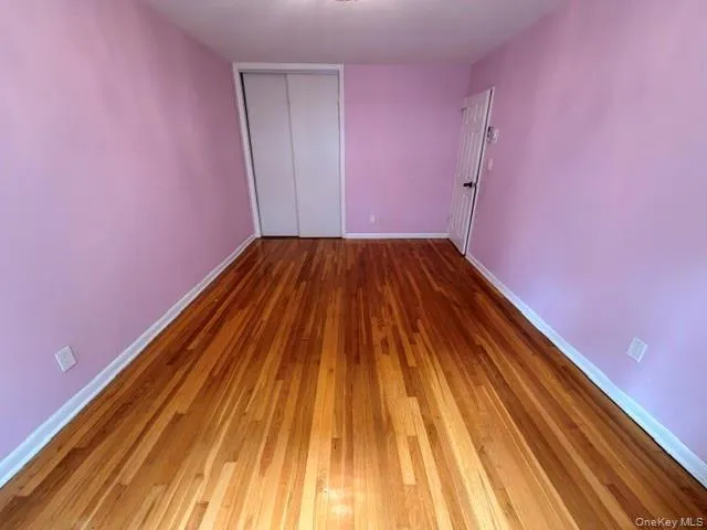 Hardwood flooring with a natural finish, white baseboards, and light pink walls Hardwood flooring with a natural finish, white baseboards, and light pink walls