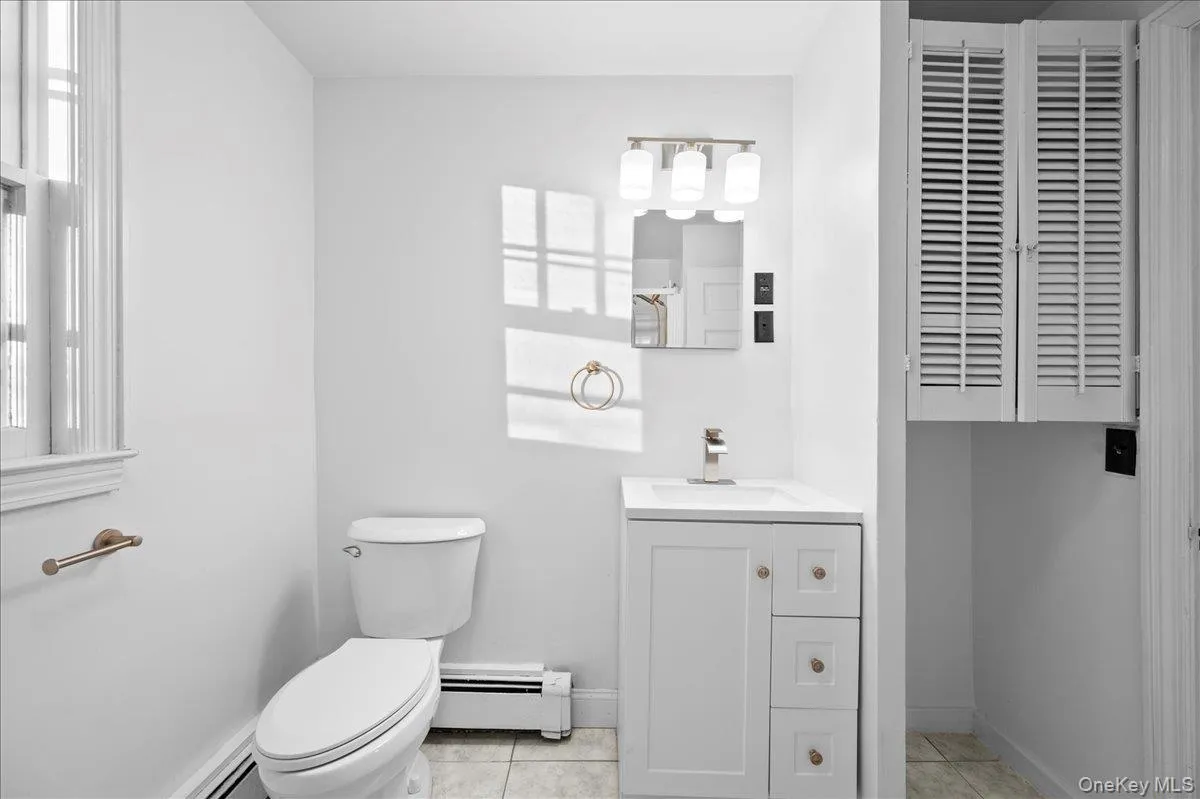 Bathroom featuring a white vanity with integrated sink, brushed nickel faucet, and three-light vanity bar Bathroom featuring a white vanity with integrated sink, brushed nickel faucet, and three-light vanity bar
