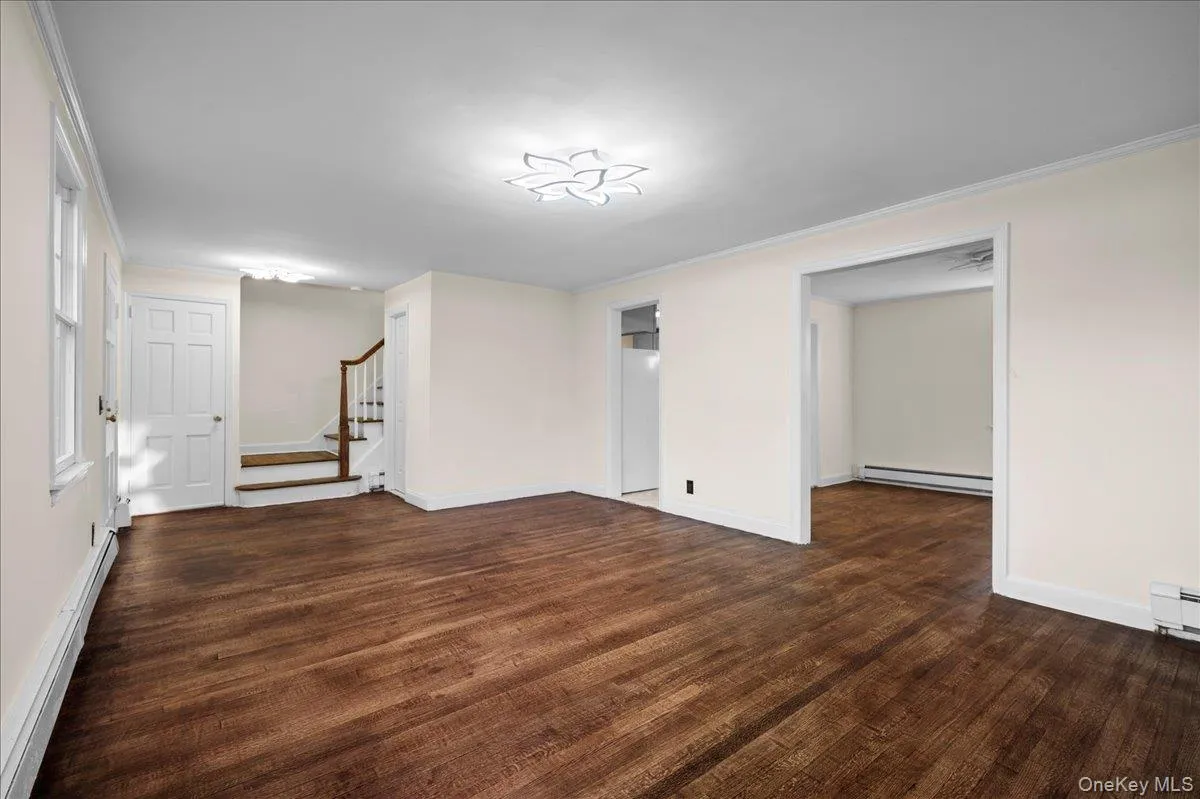 Spacious room featuring rich wood-finish flooring, light-toned walls, and white trim Spacious room featuring rich wood-finish flooring, light-toned walls, and white trim