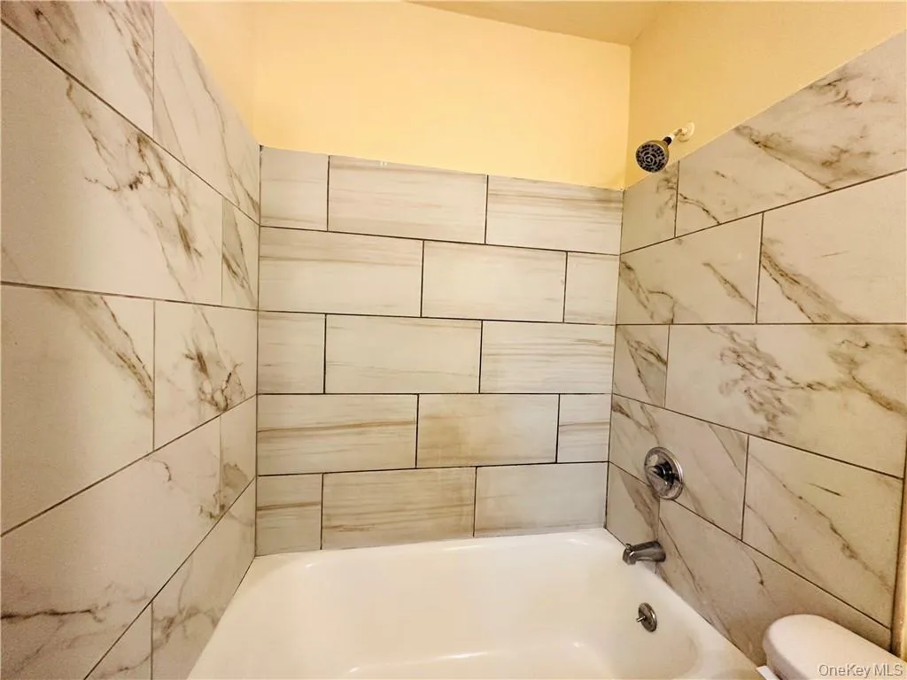 Bathroom 3 featuring tiled shower / bath and toilet Bathroom 3 featuring tiled shower / bath and toilet