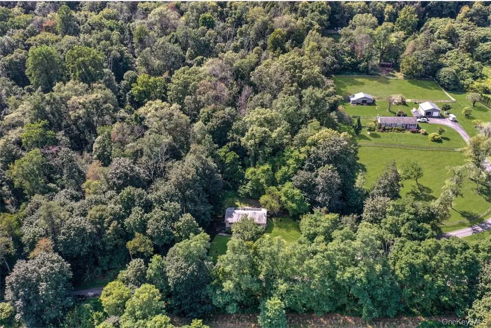 Aerial view of property and surrounding area featuring a heavily wooded area Aerial view of property and surrounding area featuring a heavily wooded area