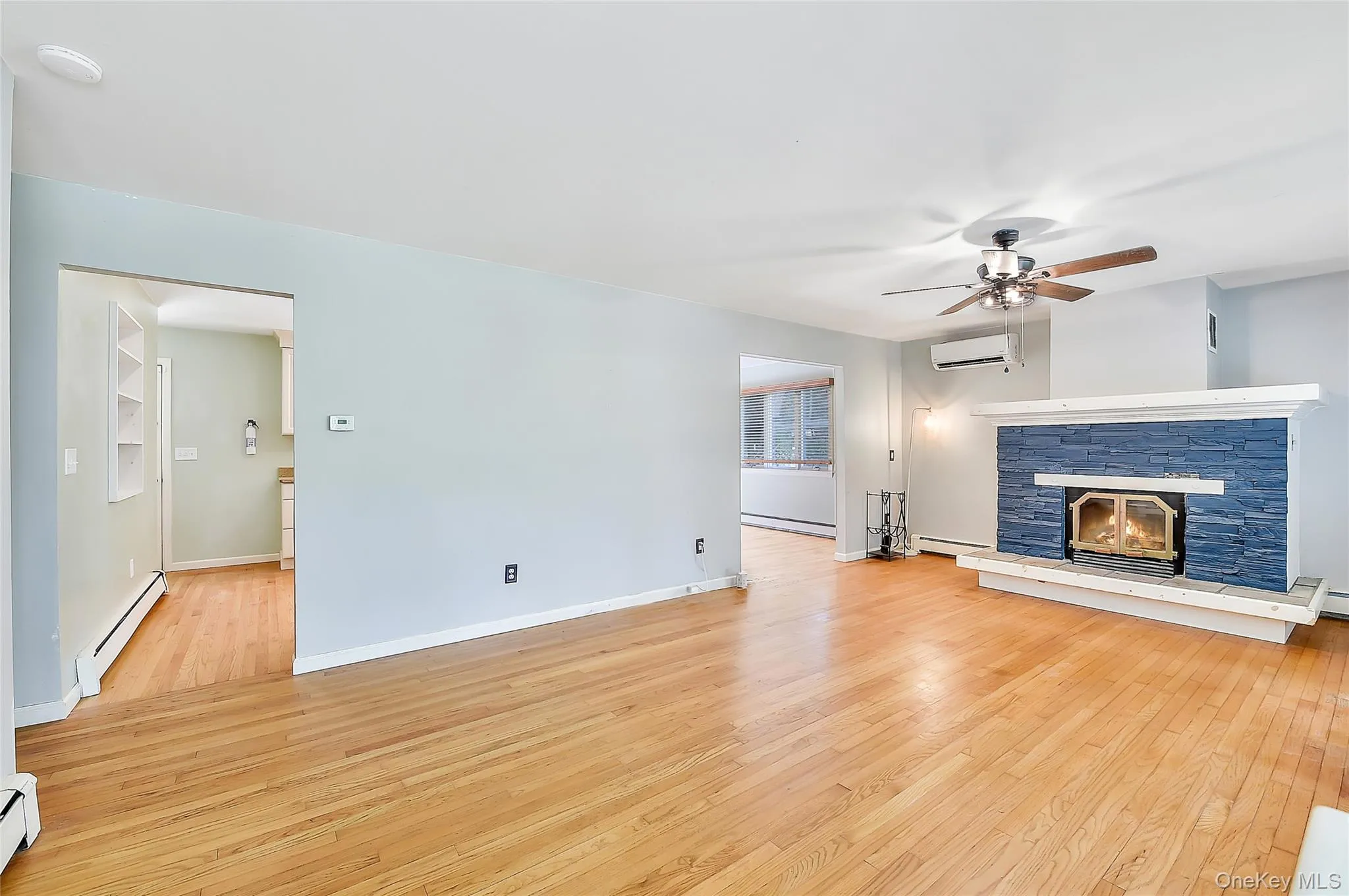 Unfurnished living room with light wood-type flooring, a fireplace, a baseboard heating unit, and a baseboard radiator Unfurnished living room with light wood-type flooring, a fireplace, a baseboard heating unit, and a baseboard radiator