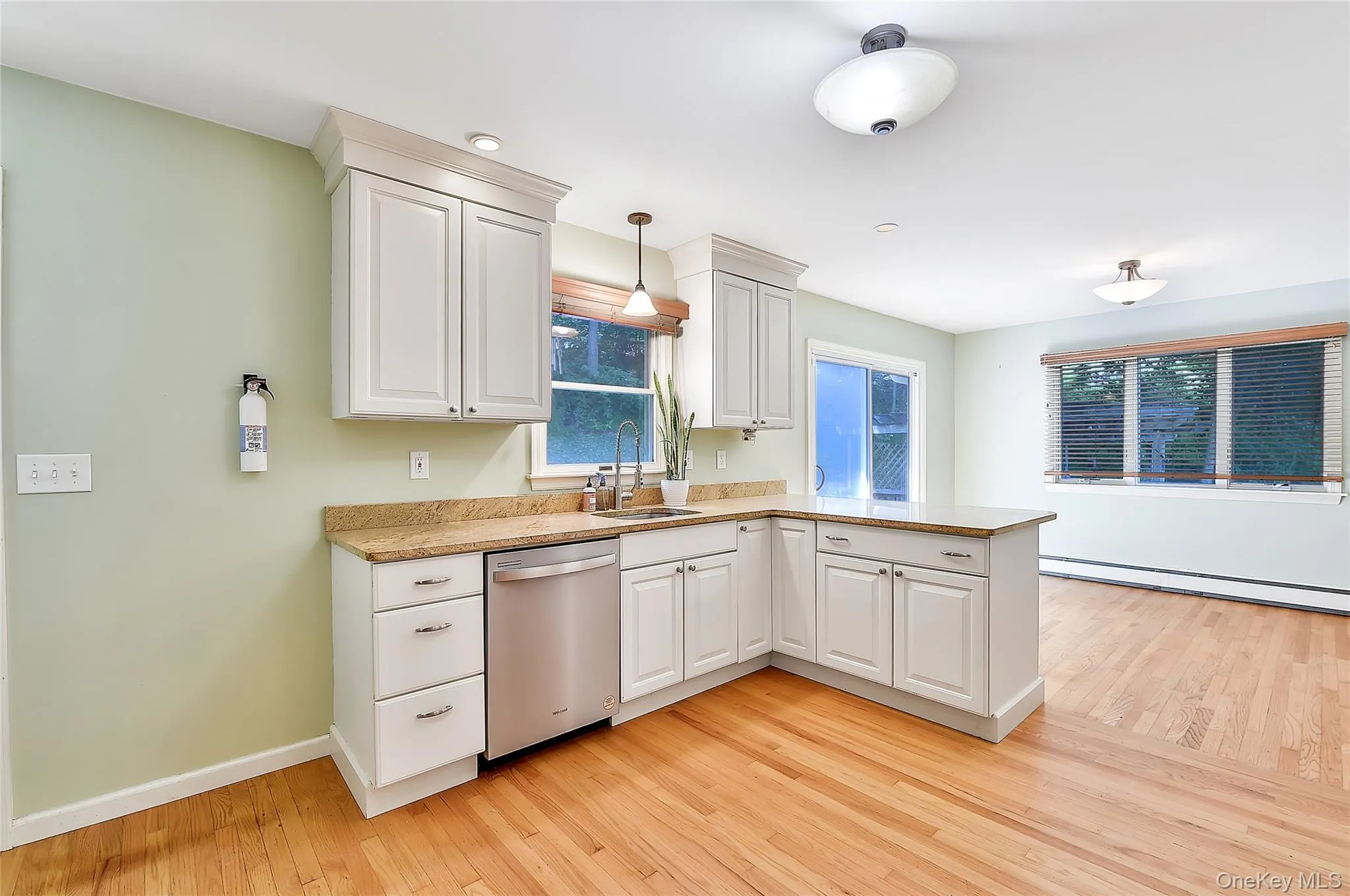 Kitchen featuring a peninsula, dishwasher, light wood-style floors, and white cabinets Kitchen featuring a peninsula, dishwasher, light wood-style floors, and white cabinets