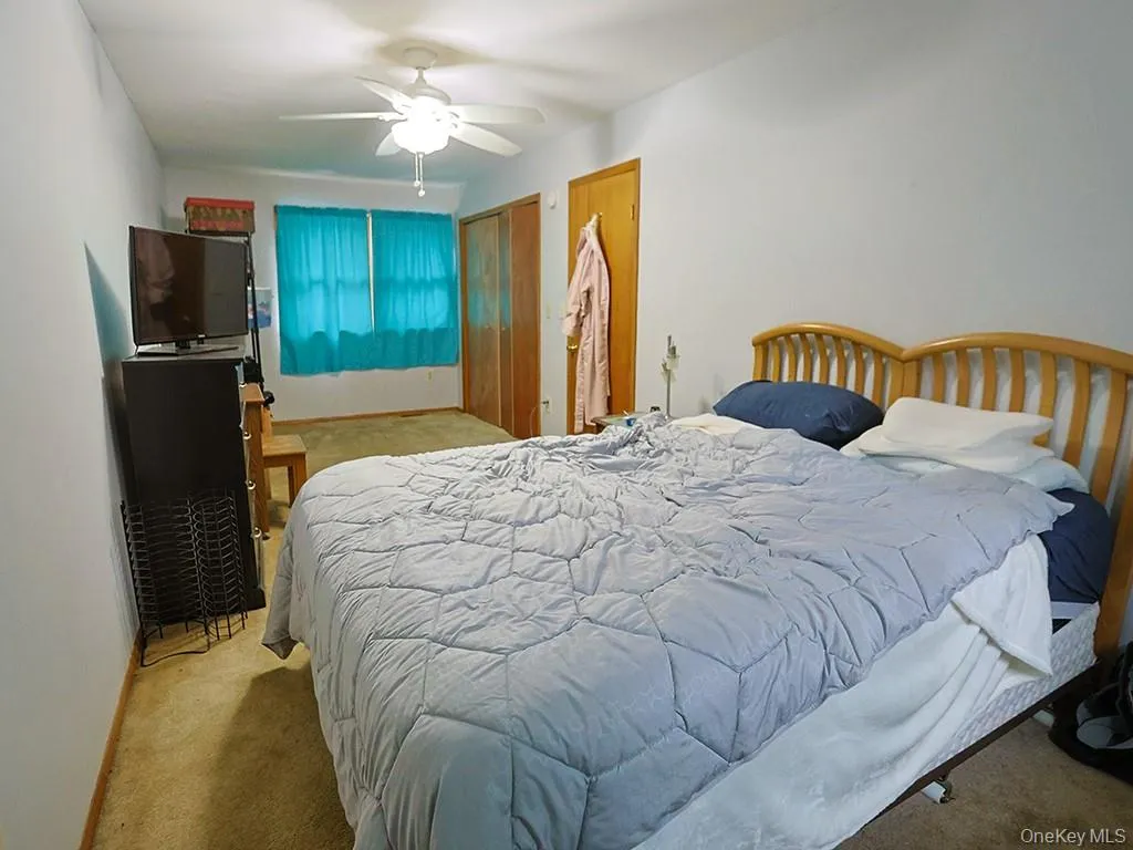 Carpeted bedroom with a ceiling fan Carpeted bedroom with a ceiling fan