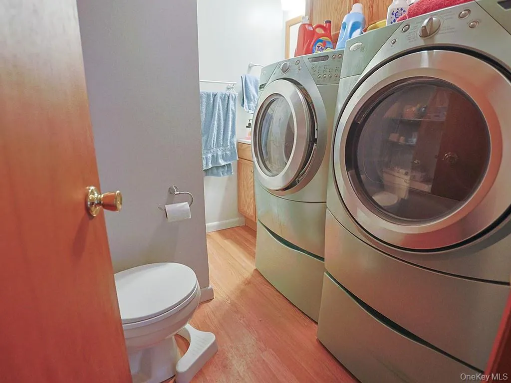 Laundry area with light wood-type flooring, washer and clothes dryer, and laundry area Laundry area with light wood-type flooring, washer and clothes dryer, and laundry area