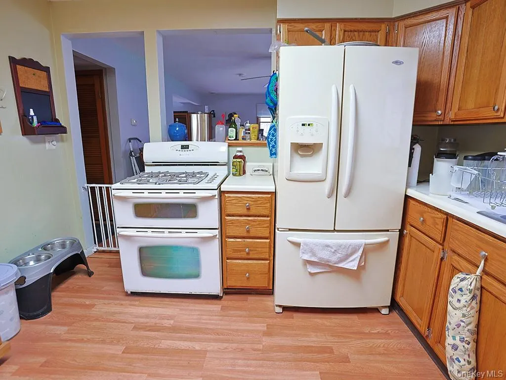 Kitchen featuring white appliances, light wood-style floors, brown cabinets, and light countertops Kitchen featuring white appliances, light wood-style floors, brown cabinets, and light countertops