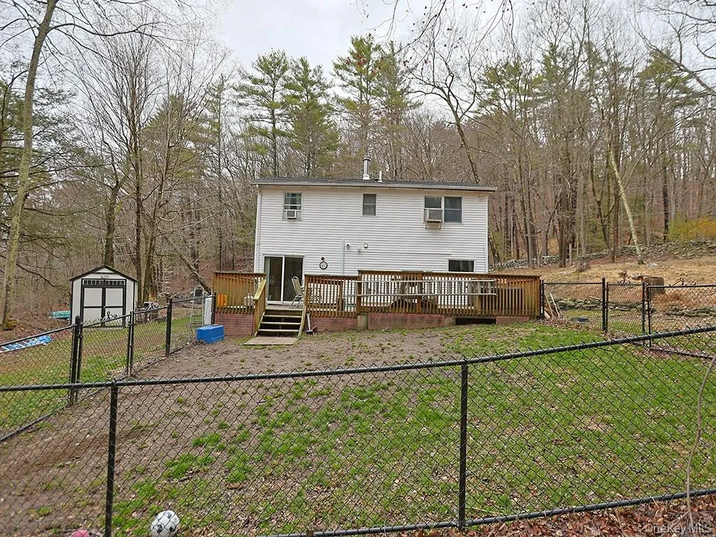 Back of house with an outbuilding, a fenced backyard, a wooden deck, and a shed Back of house with an outbuilding, a fenced backyard, a wooden deck, and a shed