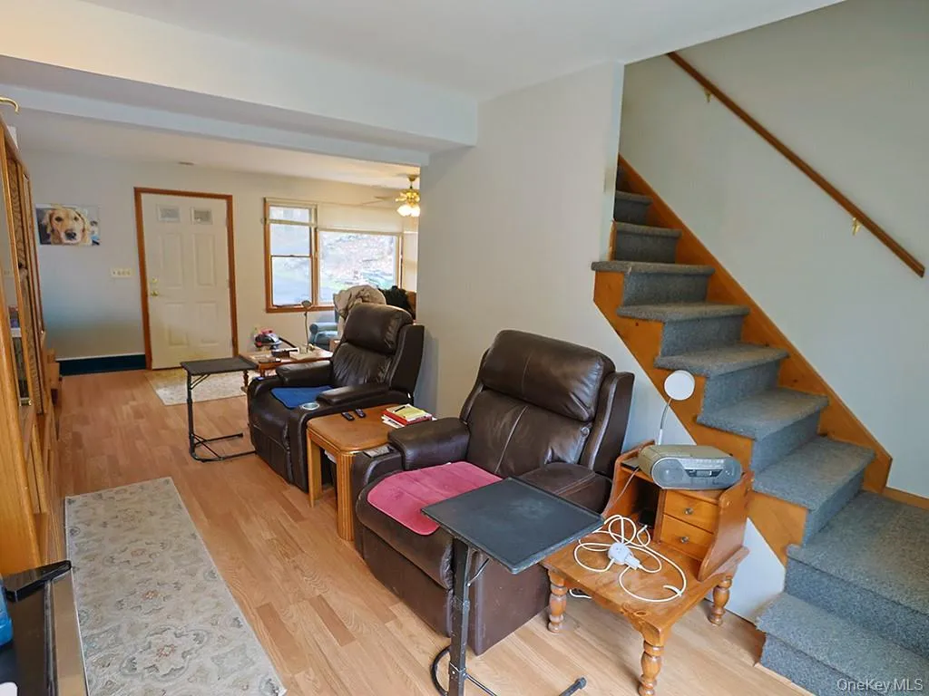 Living area featuring wood finished floors, a ceiling fan, and stairs Living area featuring wood finished floors, a ceiling fan, and stairs