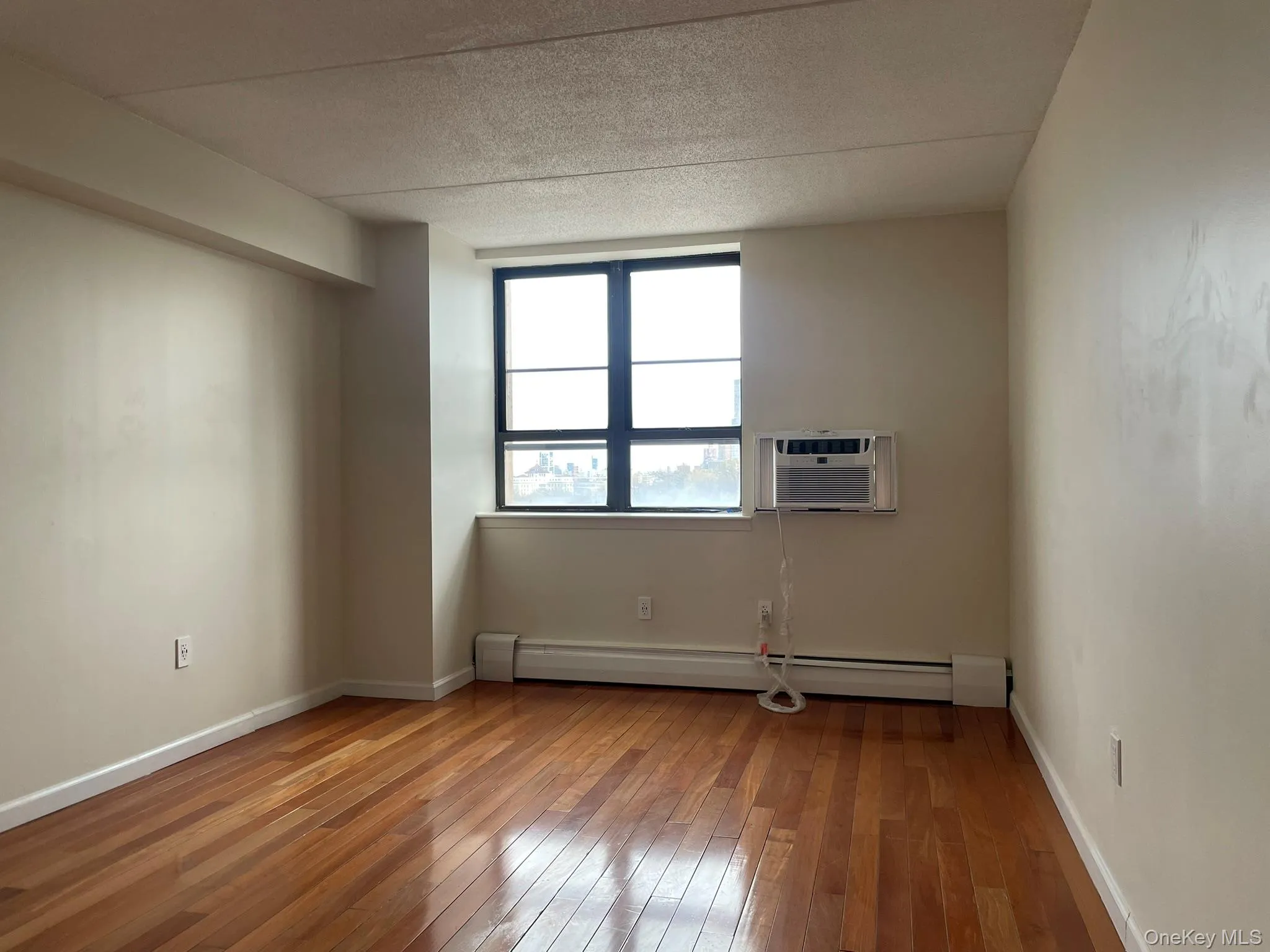 Bed room with wood-type flooring, baseboards, a baseboard heating unit, and a wall unit AC Bed room with wood-type flooring, baseboards, a baseboard heating unit, and a wall unit AC