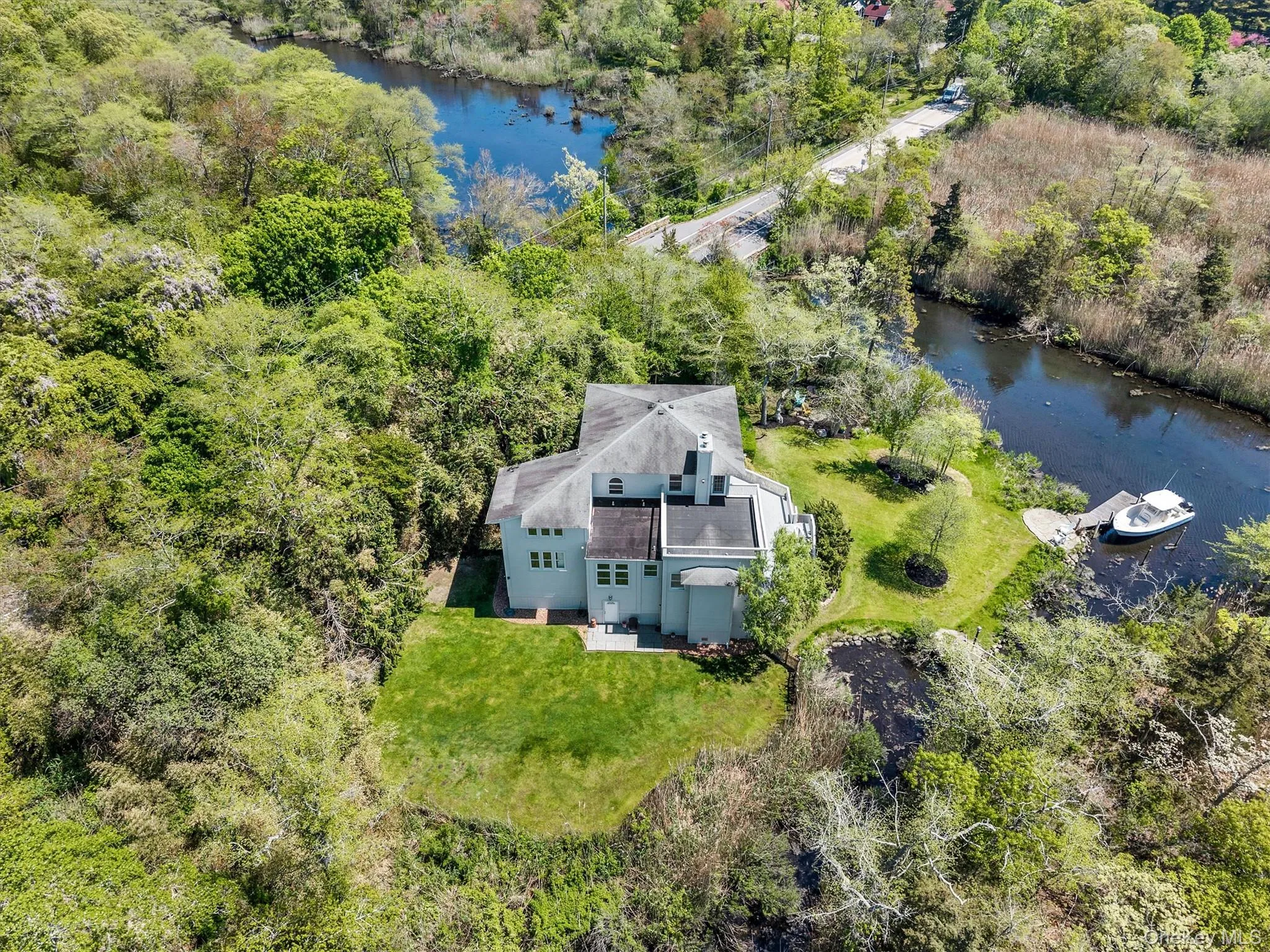 Waterfront property featuring a private boat dock, lush green lawns, mature trees, and a pond Waterfront property featuring a private boat dock, lush green lawns, mature trees, and a pond