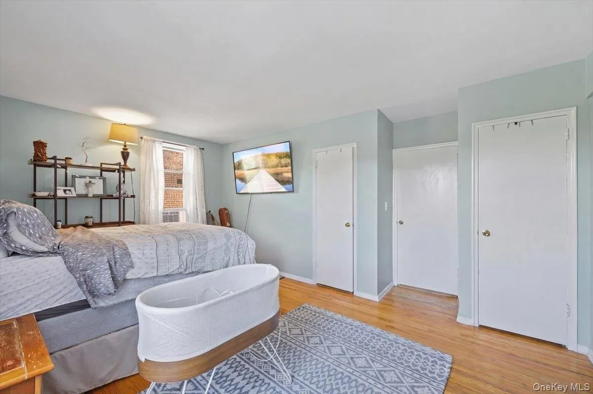 Hardwood-style flooring extends throughout this room, featuring light-toned walls and multiple white panel doors Hardwood-style flooring extends throughout this room, featuring light-toned walls and multiple white panel doors