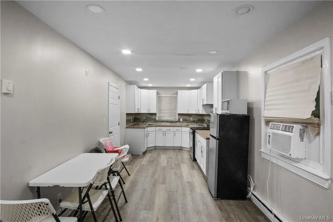 Kitchen featuring stainless steel appliances, white cabinets, sink, backsplash, and light hardwood / wood-style floors Kitchen featuring stainless steel appliances, white cabinets, sink, backsplash, and light hardwood / wood-style floors