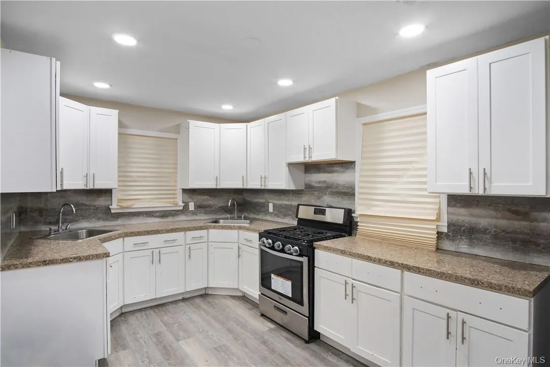 Kitchen featuring light hardwood / wood-style floors, sink, white cabinets, and gas stove Kitchen featuring light hardwood / wood-style floors, sink, white cabinets, and gas stove