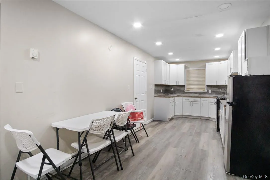 Kitchen featuring tasteful backsplash, sink, stainless steel refrigerator, light hardwood / wood-style floors, and white cabinetry Kitchen featuring tasteful backsplash, sink, stainless steel refrigerator, light hardwood / wood-style floors, and white cabinetry