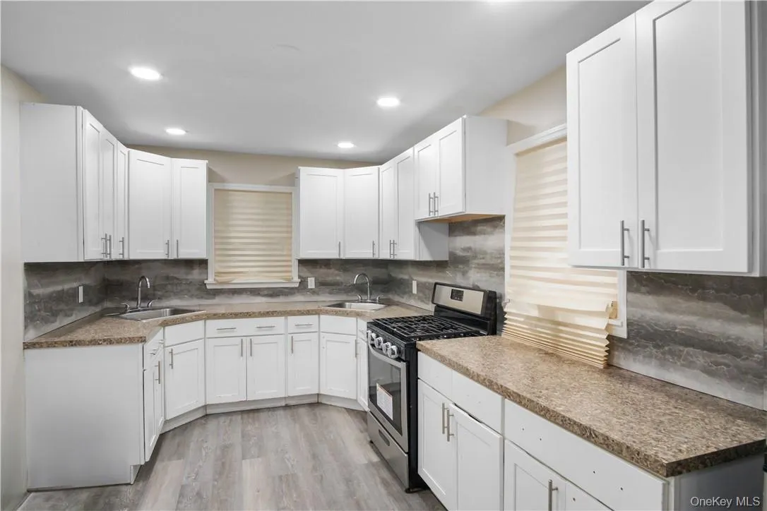 Kitchen featuring stainless steel range with gas cooktop, light hardwood / wood-style floors, and white cabinets Kitchen featuring stainless steel range with gas cooktop, light hardwood / wood-style floors, and white cabinets