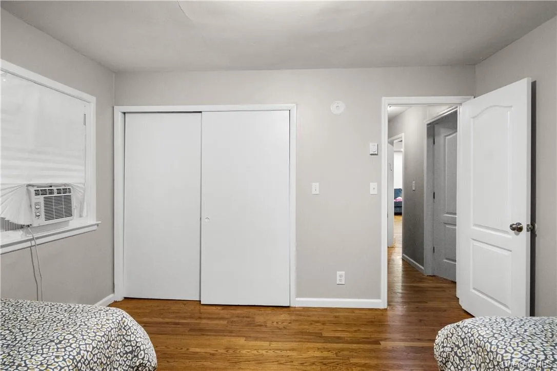 Bedroom featuring cooling unit, a closet, and wood-type flooring Bedroom featuring cooling unit, a closet, and wood-type flooring