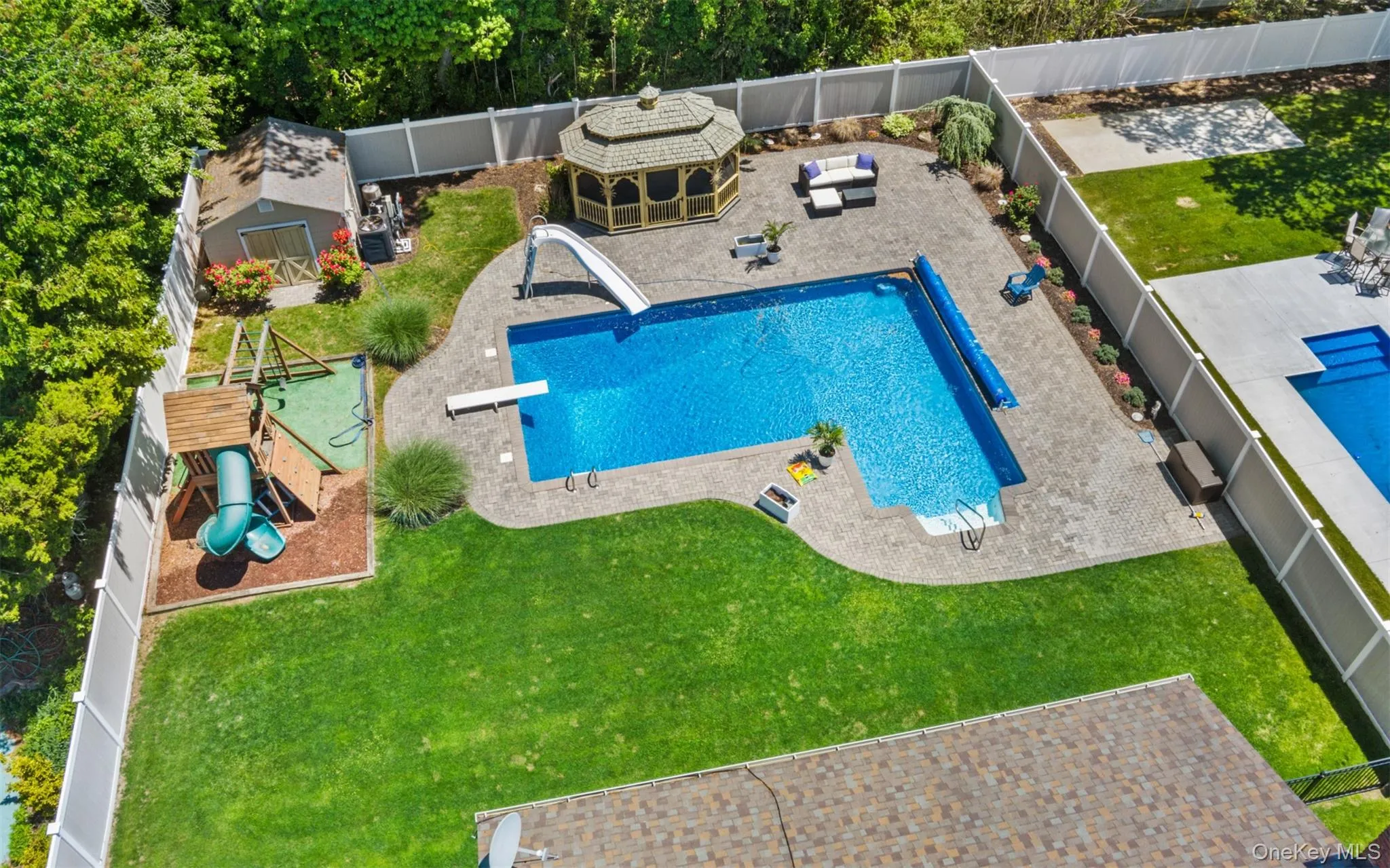 Expansive backyard featuring an in-ground pool with slide and diving board, a gazebo, and a playset on a dedicated mulch area Expansive backyard featuring an in-ground pool with slide and diving board, a gazebo, and a playset on a dedicated mulch area