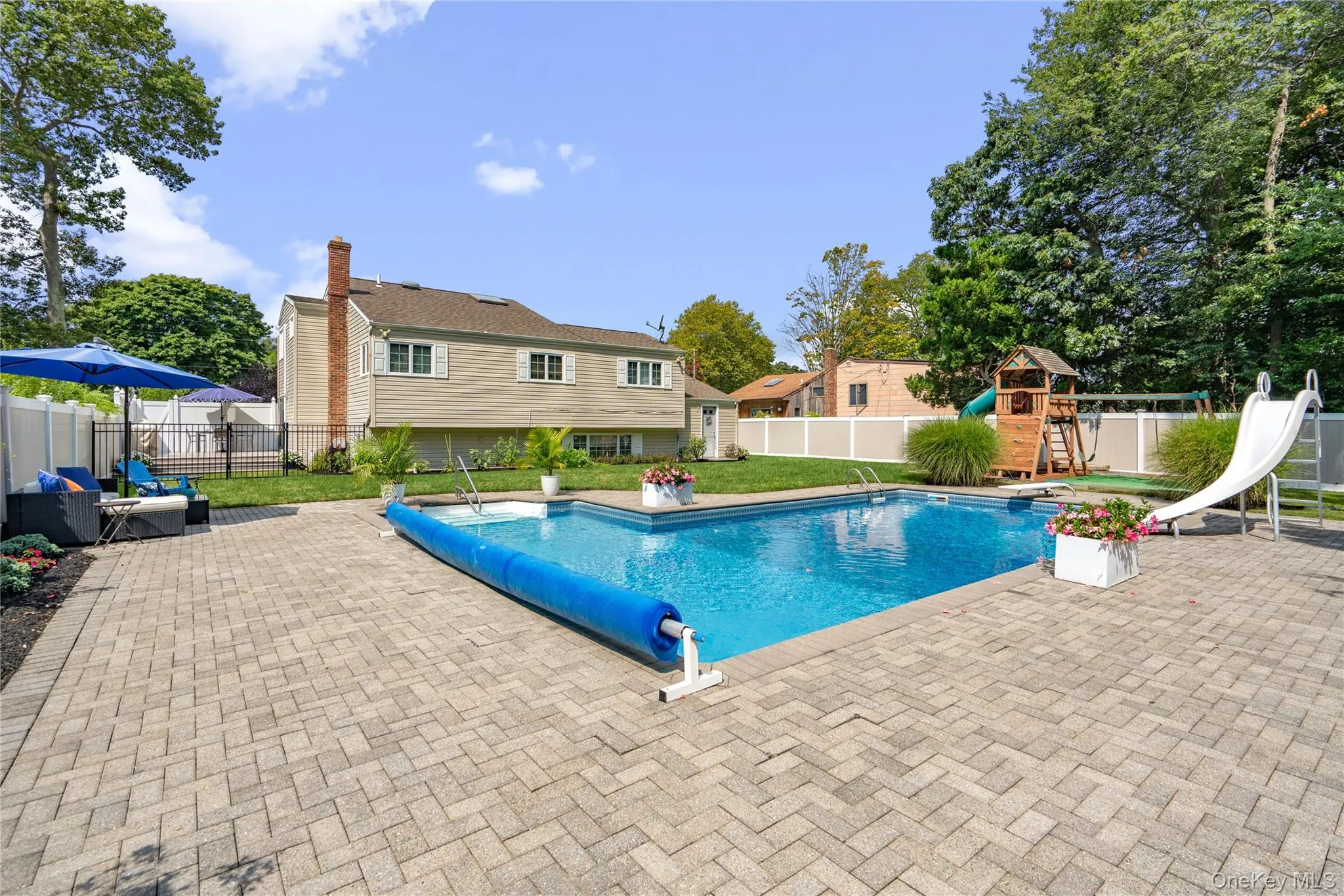 Expansive paver patio surrounding an in-ground swimming pool Expansive paver patio surrounding an in-ground swimming pool