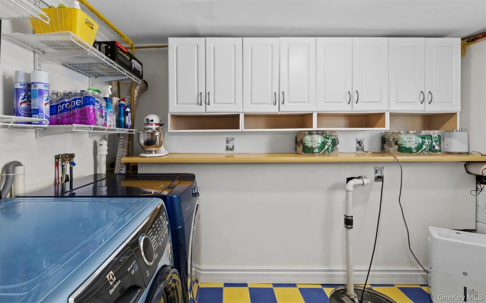 Dedicated utility area featuring white wall cabinetry, a light wood-finish countertop, and wire shelving for organization Dedicated utility area featuring white wall cabinetry, a light wood-finish countertop, and wire shelving for organization