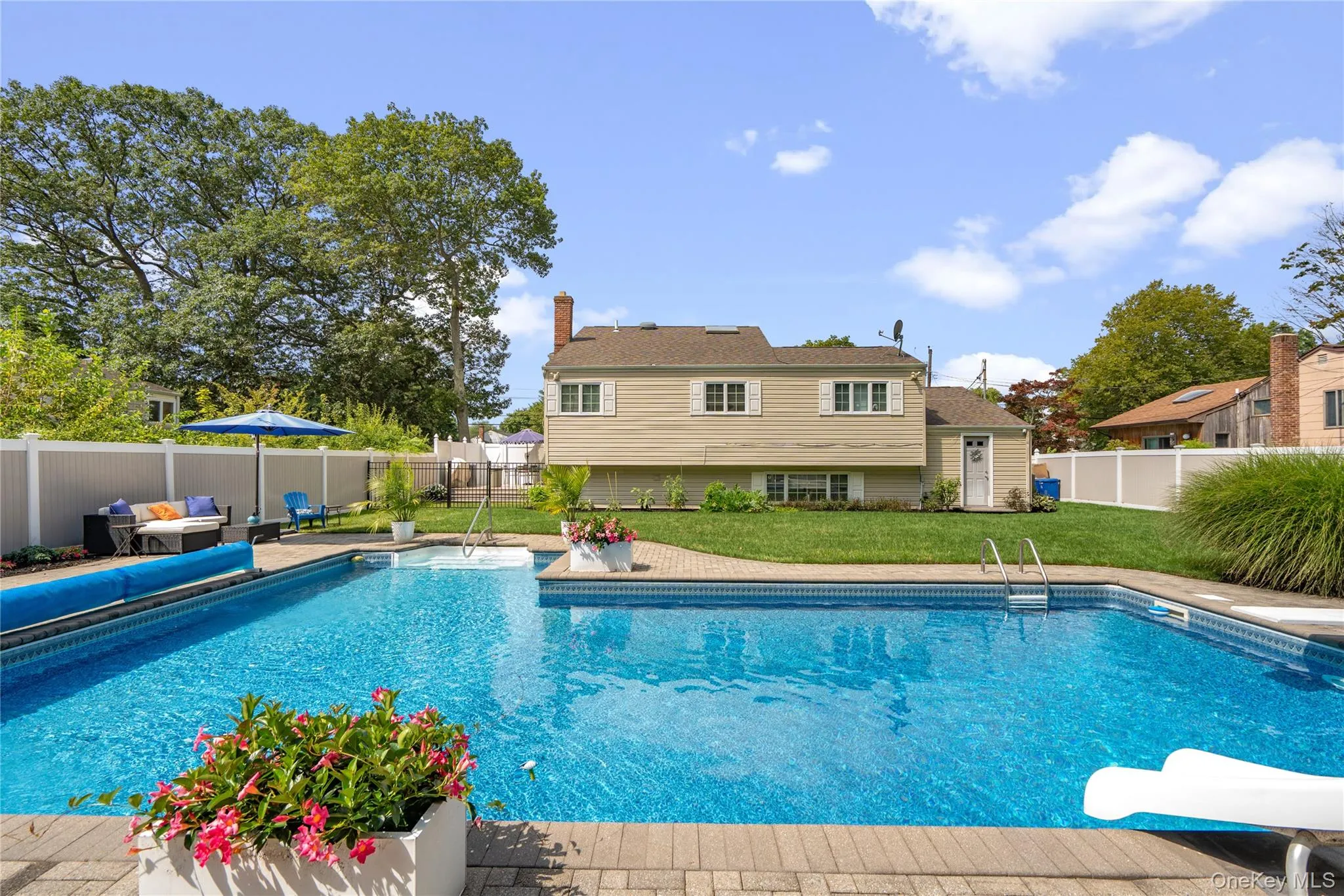 L-shaped swimming pool with blue tile detailing, surrounded by a paver patio L-shaped swimming pool with blue tile detailing, surrounded by a paver patio