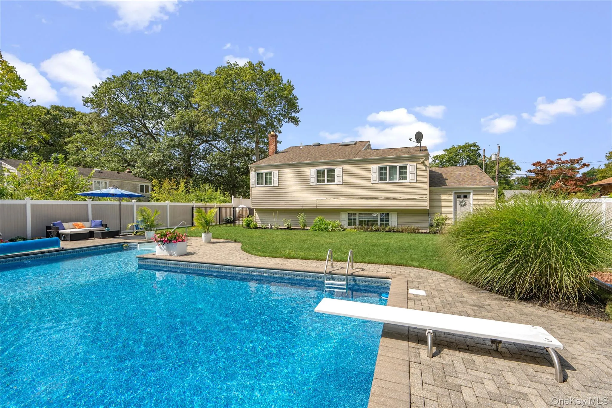 Expansive backyard featuring a large swimming pool, diving board, and paver patio Expansive backyard featuring a large swimming pool, diving board, and paver patio