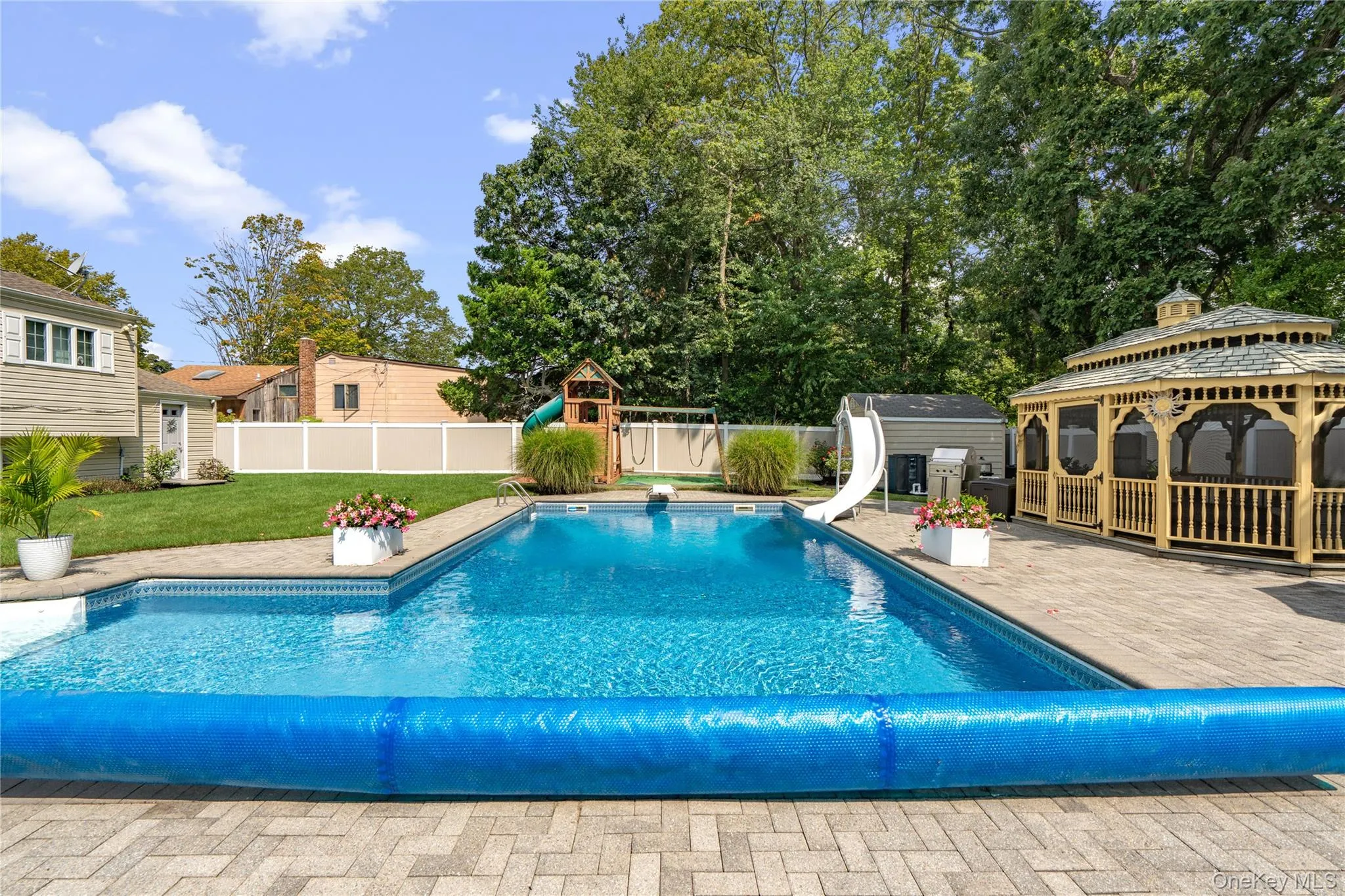 Expansive backyard featuring an in-ground swimming pool, a light wood gazebo with screened openings, a utility shed, and mature perimeter trees Expansive backyard featuring an in-ground swimming pool, a light wood gazebo with screened openings, a utility shed, and mature perimeter trees