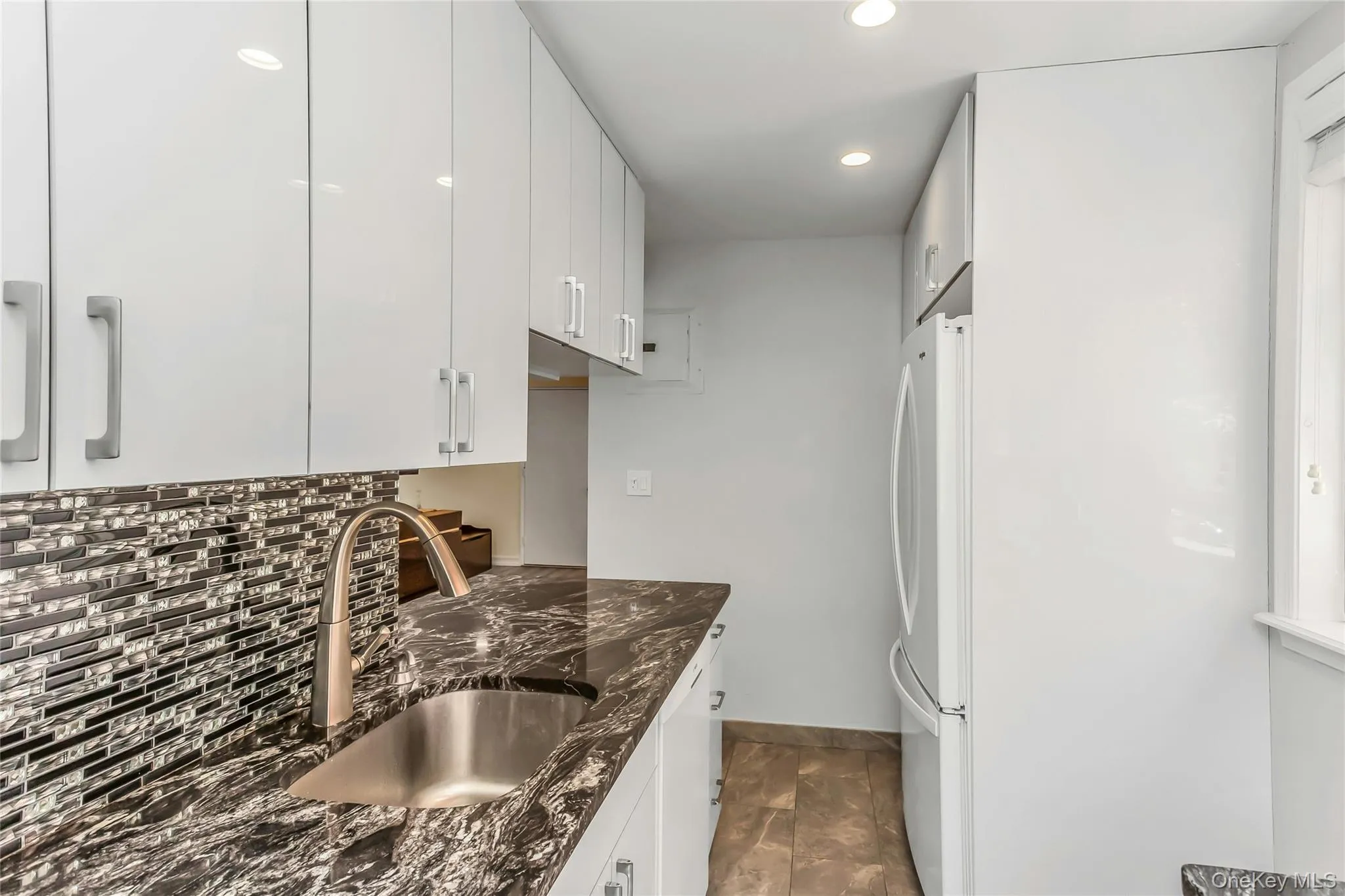 Kitchen featuring white flat-panel cabinetry, a stainless steel undermount sink, and a gooseneck faucet Kitchen featuring white flat-panel cabinetry, a stainless steel undermount sink, and a gooseneck faucet