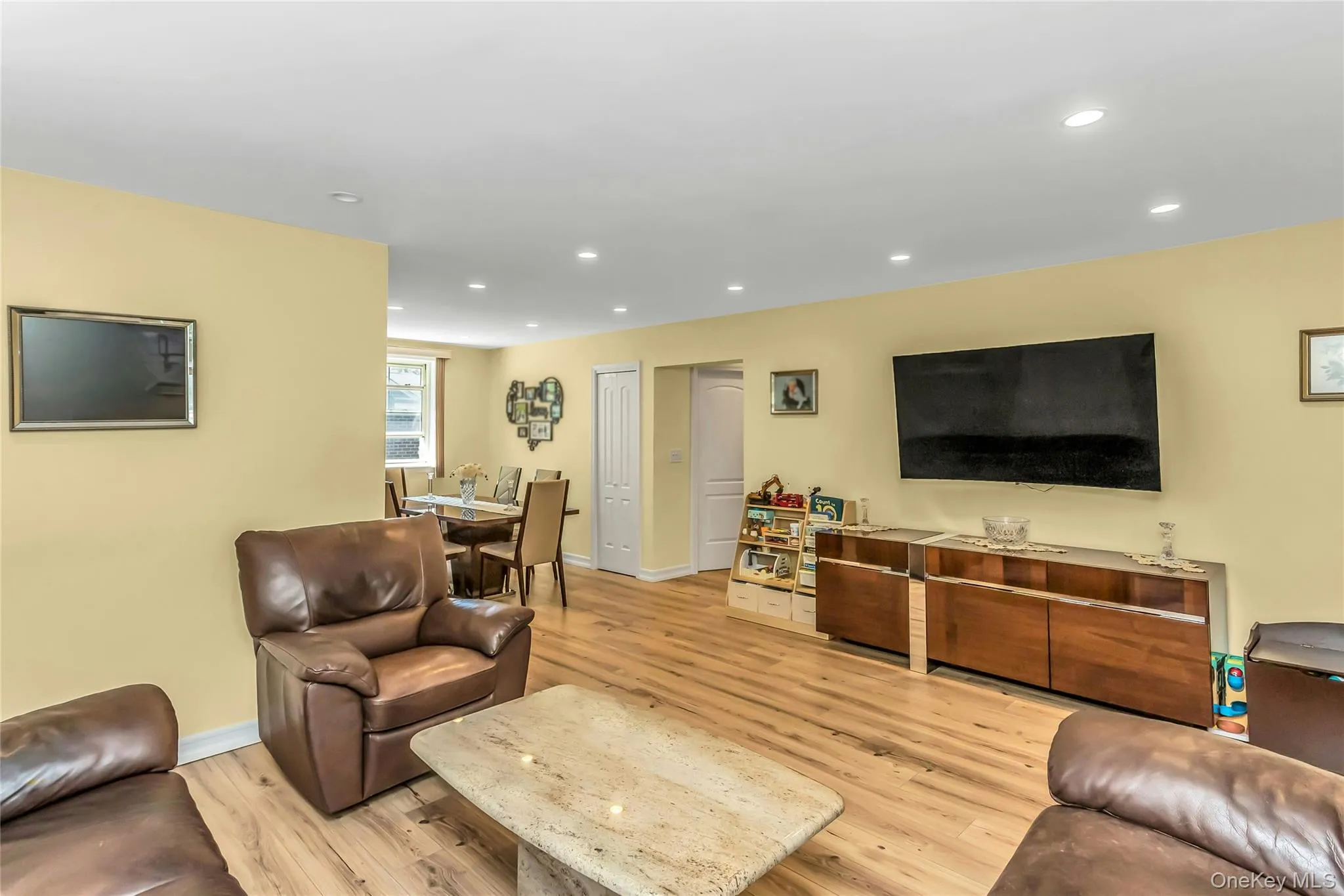Open-concept living space featuring recessed lighting, wood-finish flooring, and a dining area with a window Open-concept living space featuring recessed lighting, wood-finish flooring, and a dining area with a window