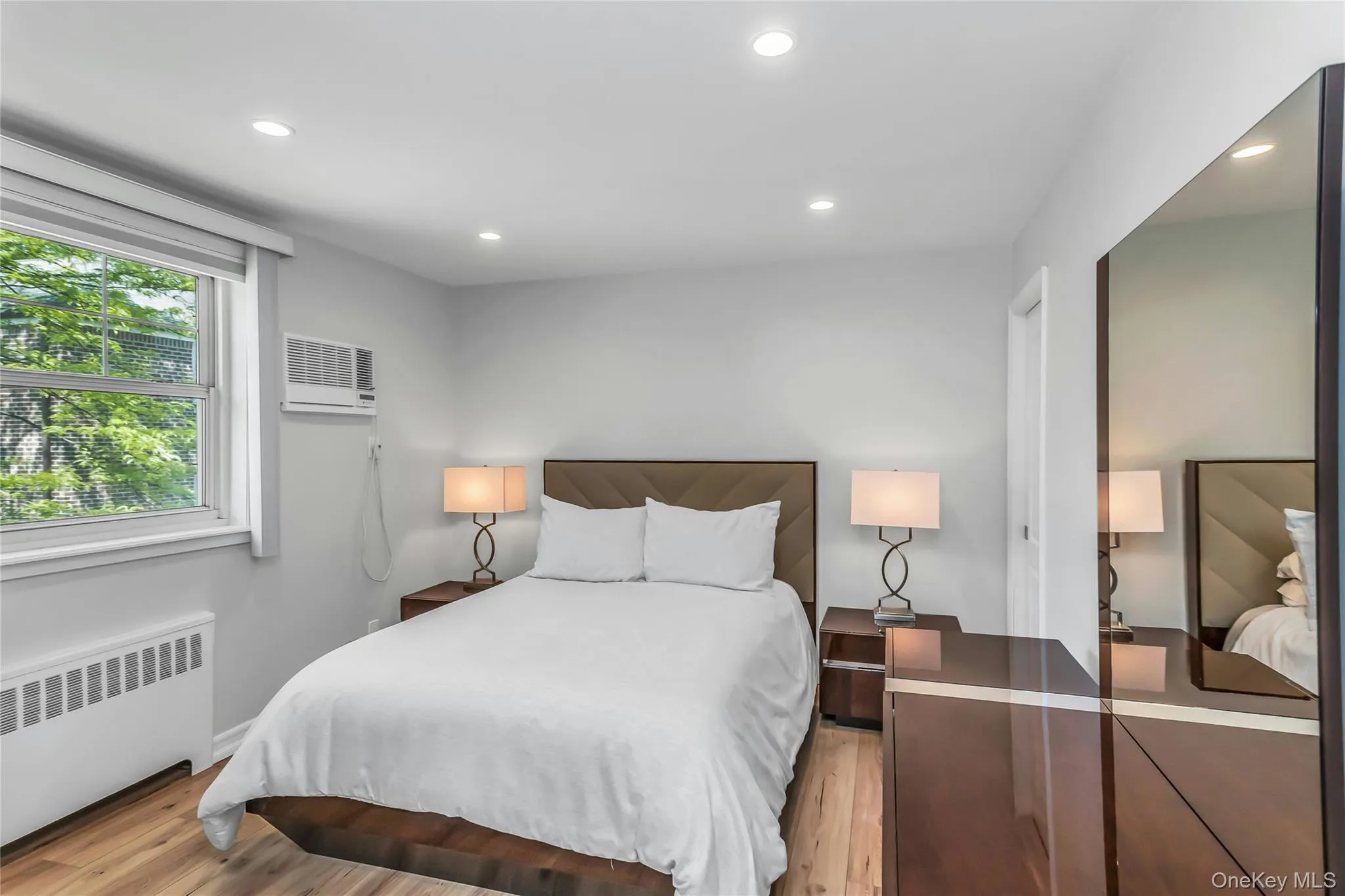 Primary bedroom featuring wood-finish flooring and recessed ceiling lighting Primary bedroom featuring wood-finish flooring and recessed ceiling lighting