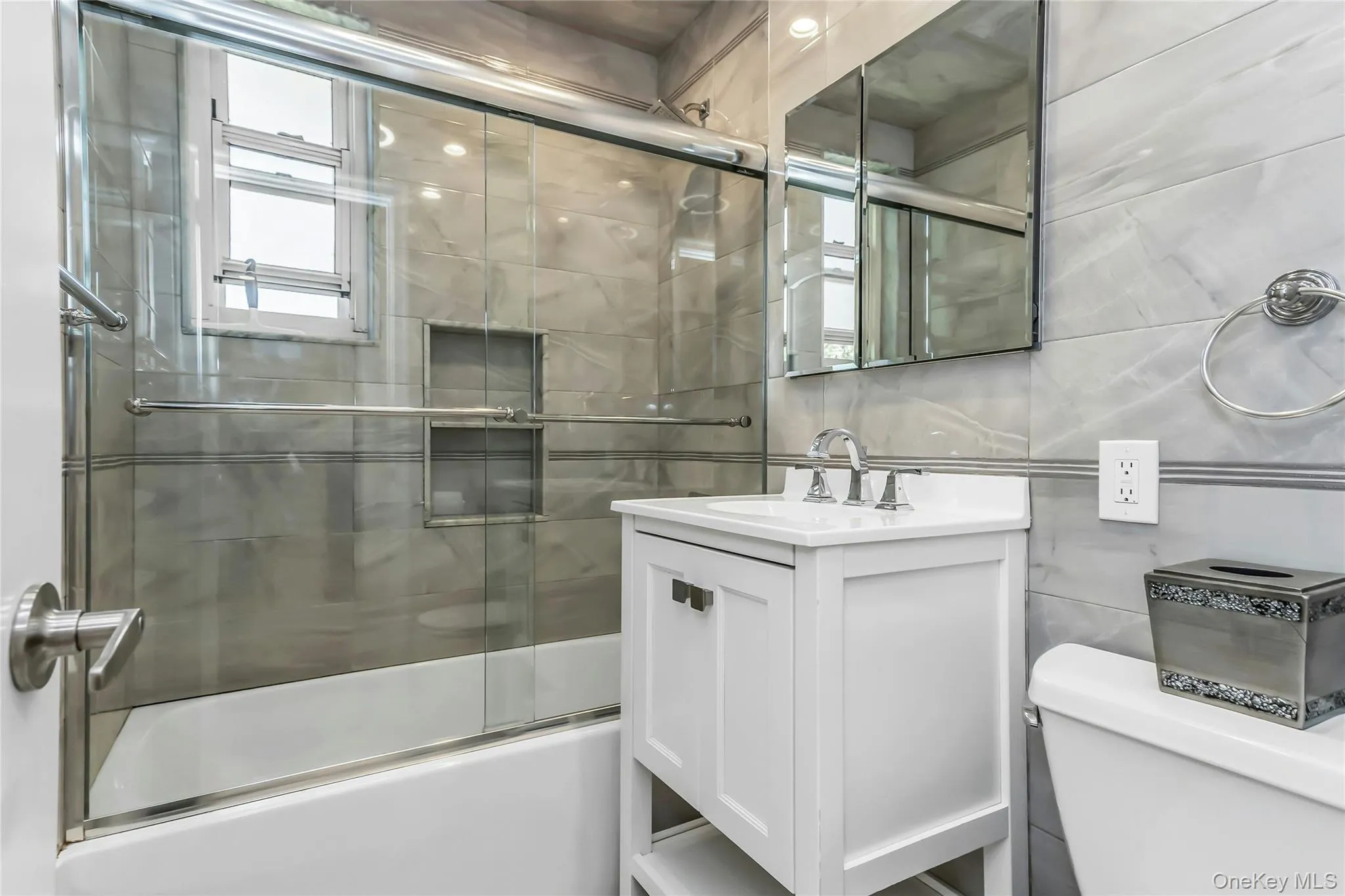 Full bathroom featuring a white vanity with integrated sink, chrome faucet, and mirrored medicine cabinet Full bathroom featuring a white vanity with integrated sink, chrome faucet, and mirrored medicine cabinet