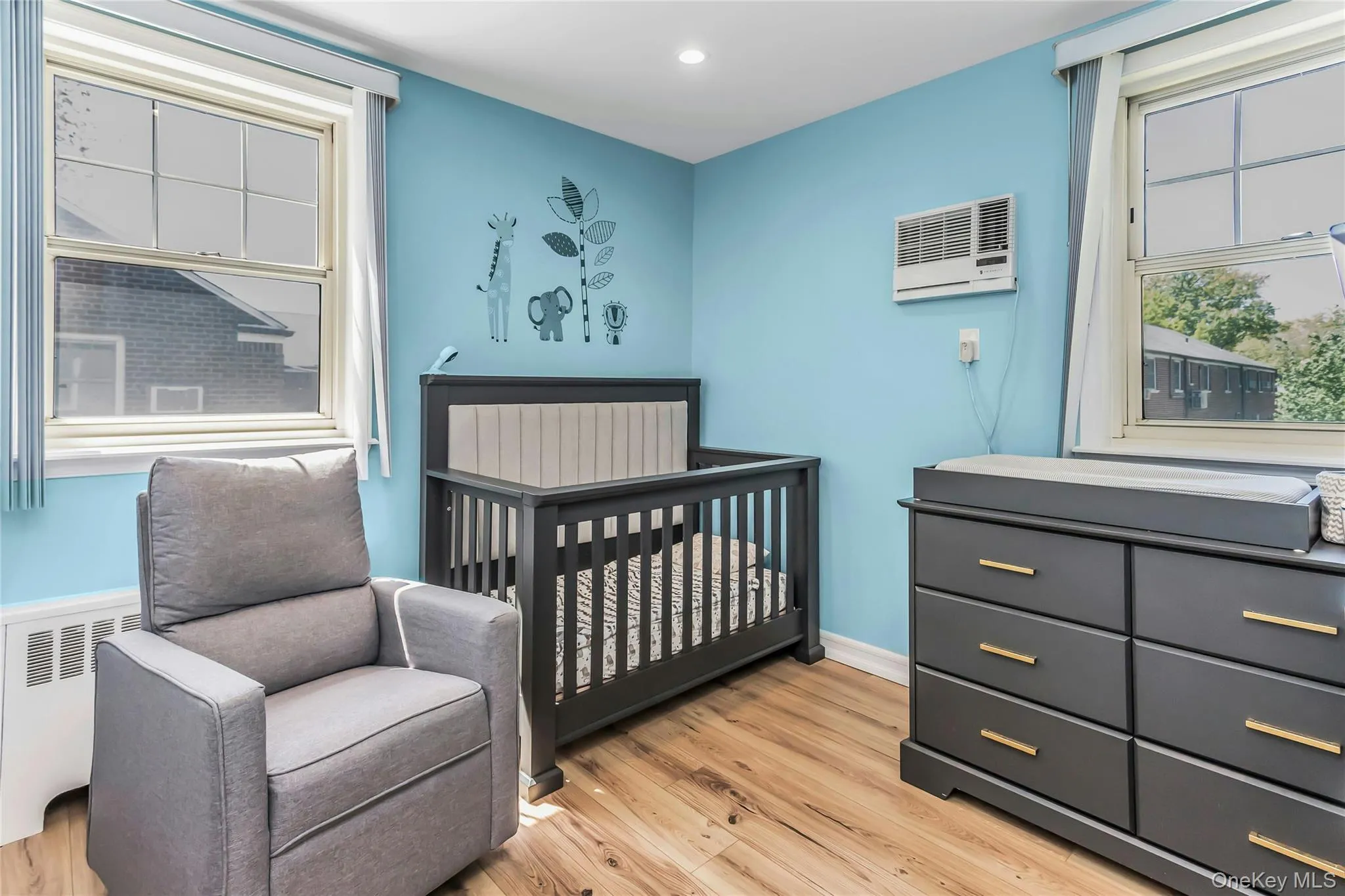 Second bedroom with plenty of natural light, wall-mounted air conditioning unit, and a baseboard heating unit Second bedroom with plenty of natural light, wall-mounted air conditioning unit, and a baseboard heating unit