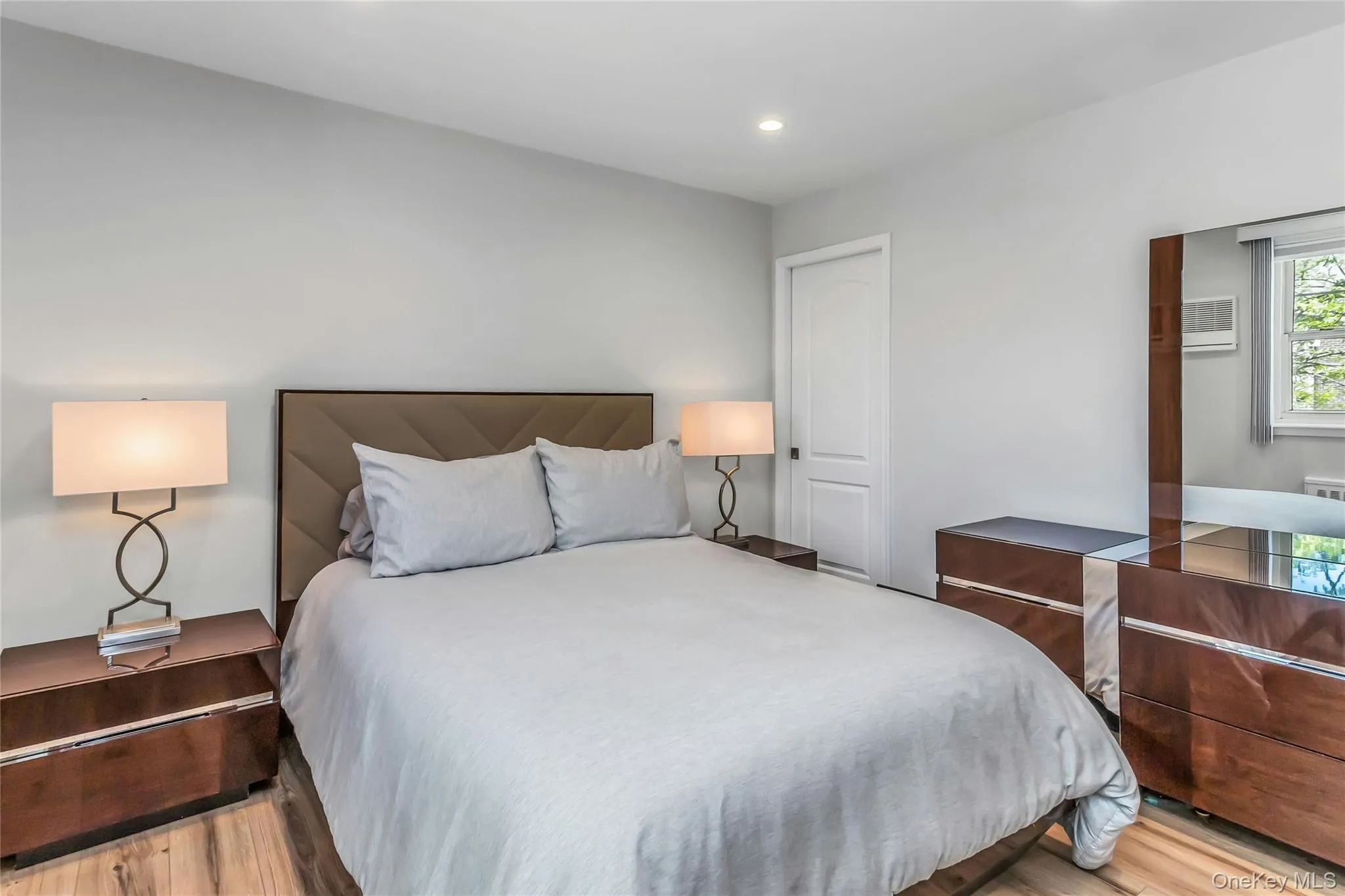 Primary bedroom featuring neutral wall color, recessed lighting, and wood-finish flooring Primary bedroom featuring neutral wall color, recessed lighting, and wood-finish flooring