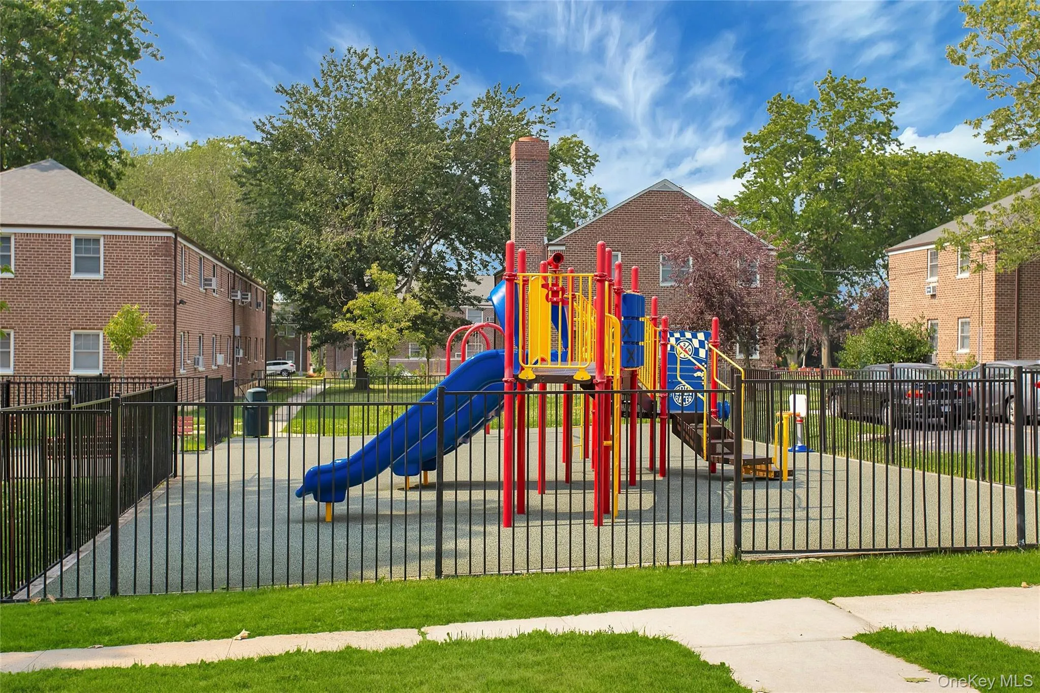 Fenced outdoor play structure featuring slides, ladders, and activity panels on a soft-surface ground cover Fenced outdoor play structure featuring slides, ladders, and activity panels on a soft-surface ground cover
