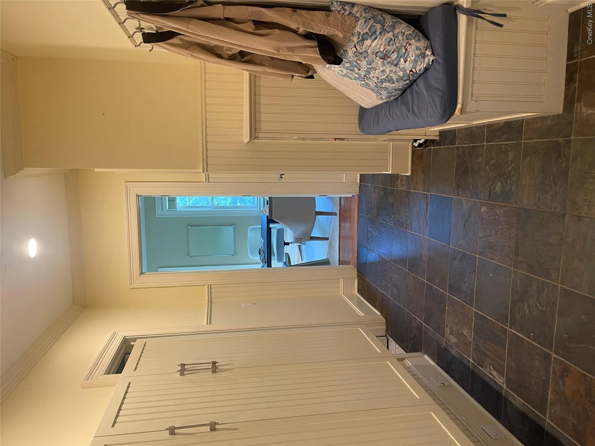 Main level mudroom with slate floor tile, storage cubbies, coat hooks, coat closet, sink, door to garage, doggie door, door to windowed laundry room (not shown), full bath and office/5th bedroom Main level mudroom with slate floor tile, storage cubbies, coat hooks, coat closet, sink, door to garage, doggie door, door to windowed laundry room (not shown), full bath and office/5th bedroom
