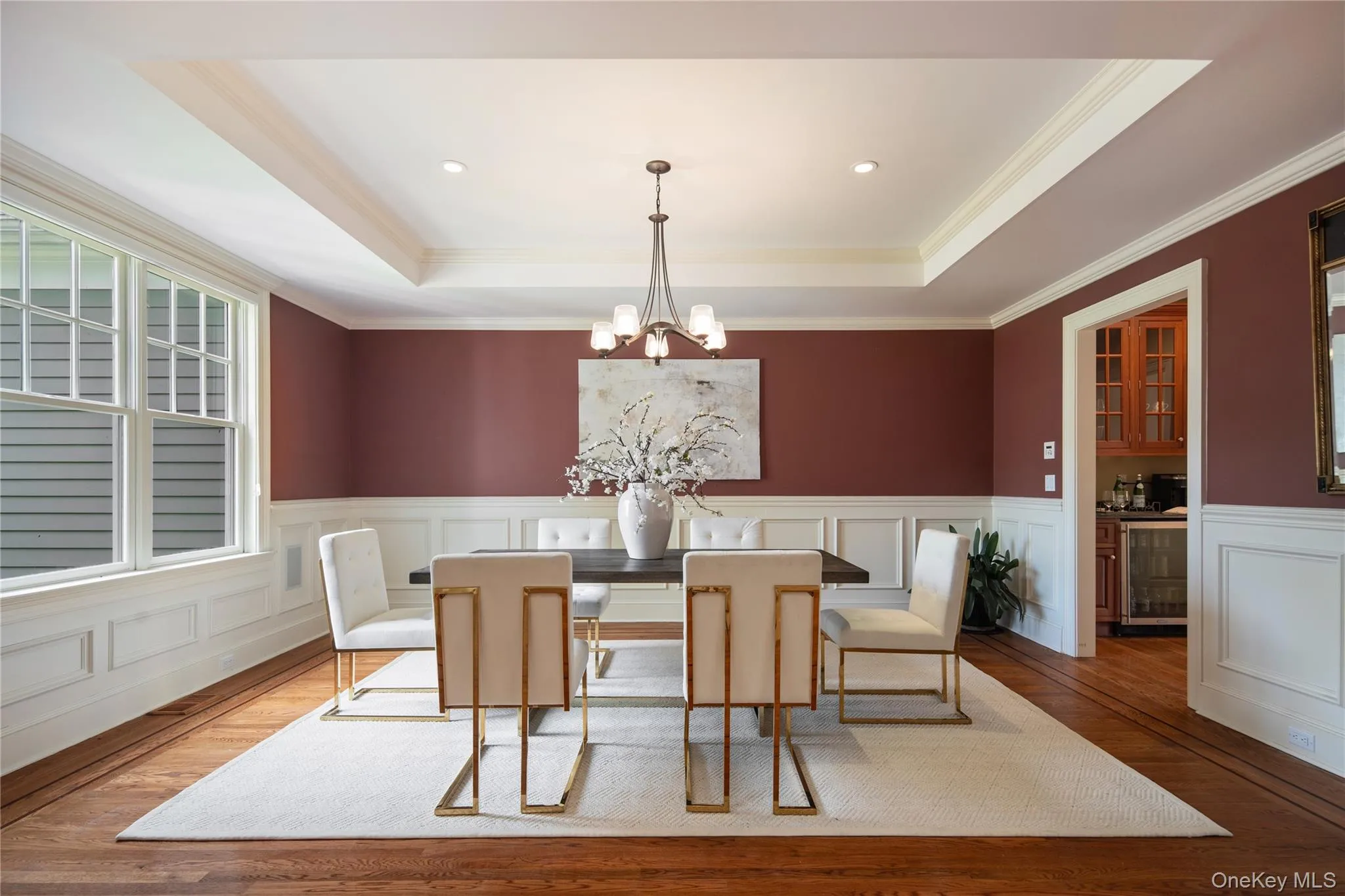 Formal dining room features a tray ceiling, wainscot wall panels, crown molding, and entry to the butlers pantry and eat-in kitchen Formal dining room features a tray ceiling, wainscot wall panels, crown molding, and entry to the butlers pantry and eat-in kitchen