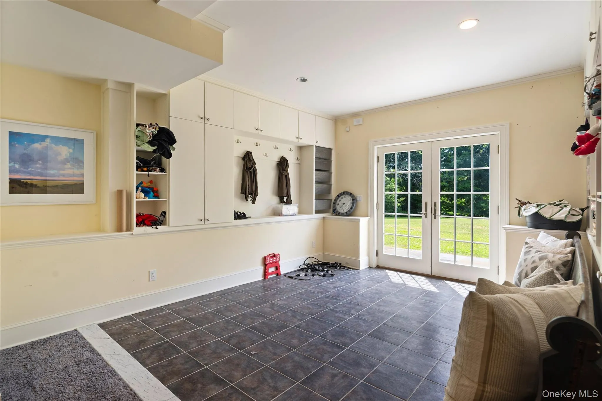 Lower level mudroom with storage cabinetry, coat hooks and cubbys, French doors out to back yard, tile floor Lower level mudroom with storage cabinetry, coat hooks and cubbys, French doors out to back yard, tile floor