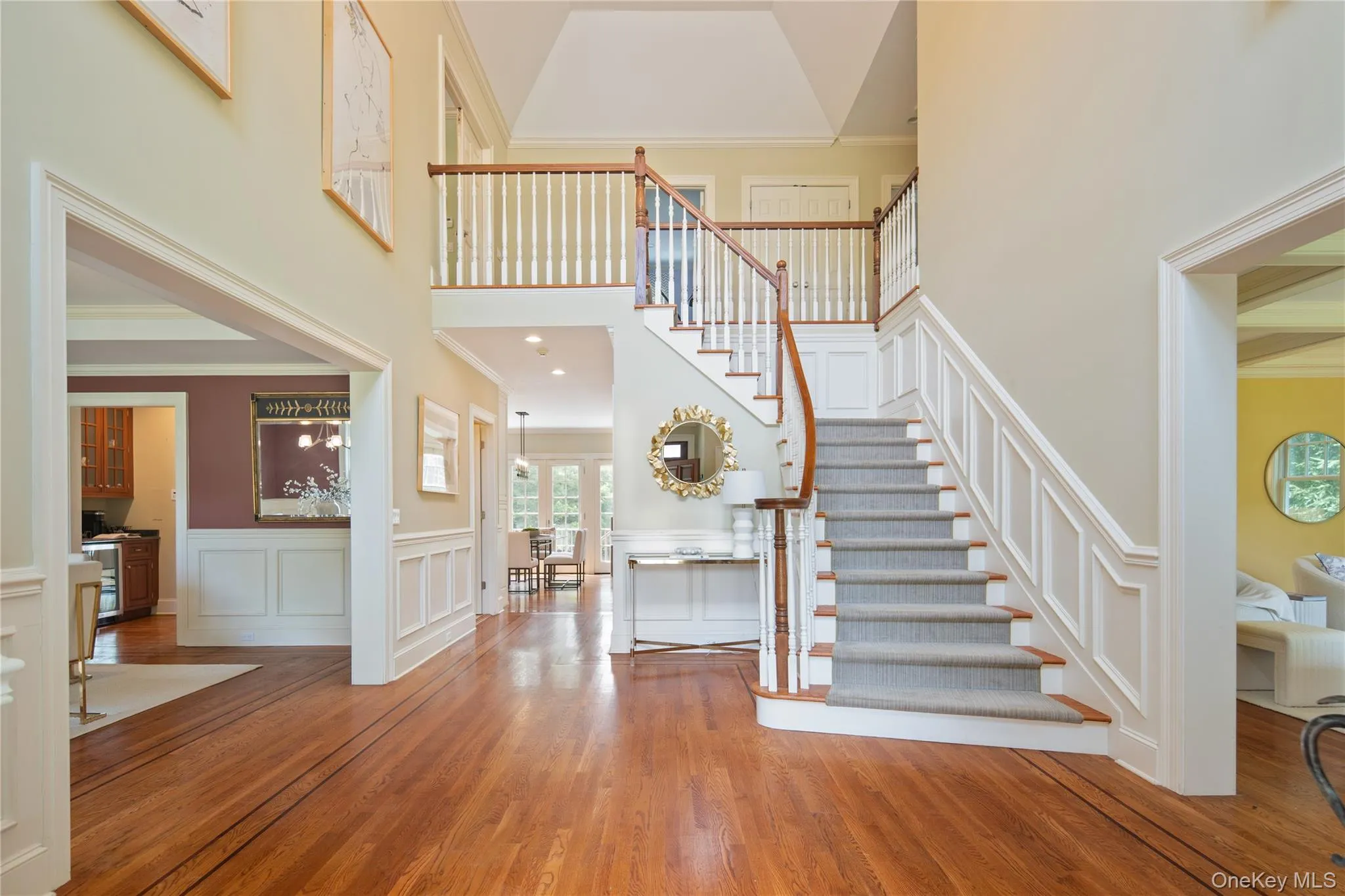 The double height entry has a turned stair, wall panels, two coat closets, a powder room and gracious open entry to the formal living room on right and formal dining room on left, oak hardwood floors with walnut borders, eclectic wench for light fixture The double height entry has a turned stair, wall panels, two coat closets, a powder room and gracious open entry to the formal living room on right and formal dining room on left, oak hardwood floors with walnut borders, eclectic wench for light fixture