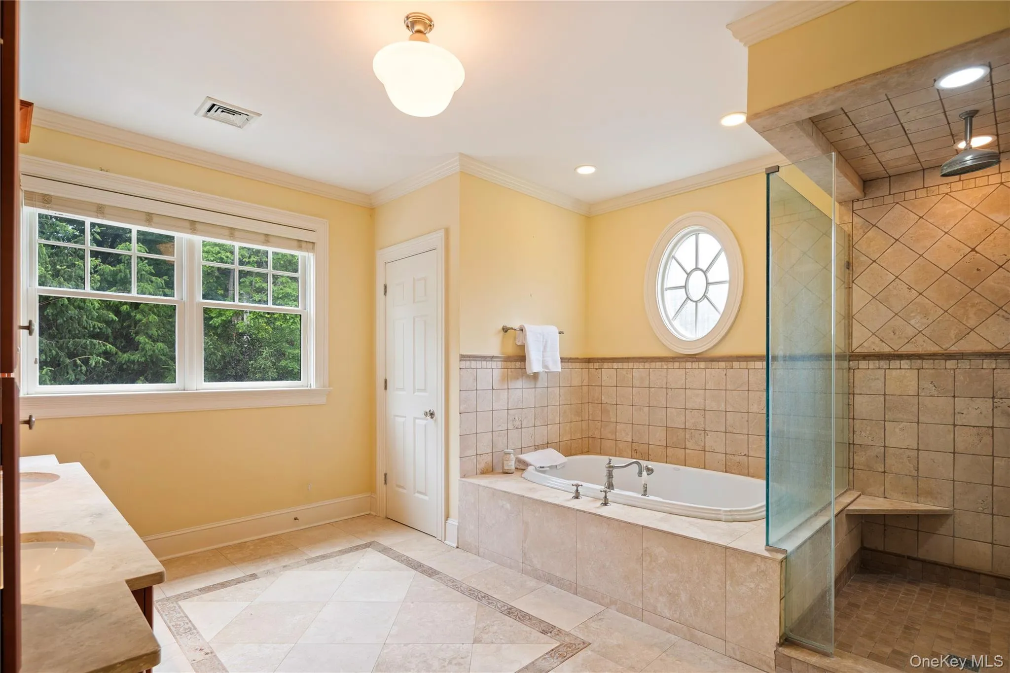 En-suite marble spa style primary bath features jetted tub, separate shower, custom double vanity with storage towers and dual undermount sinks, frameless glass shower enclosure, separate water closet, recessed lighting, crown molding En-suite marble spa style primary bath features jetted tub, separate shower, custom double vanity with storage towers and dual undermount sinks, frameless glass shower enclosure, separate water closet, recessed lighting, crown molding