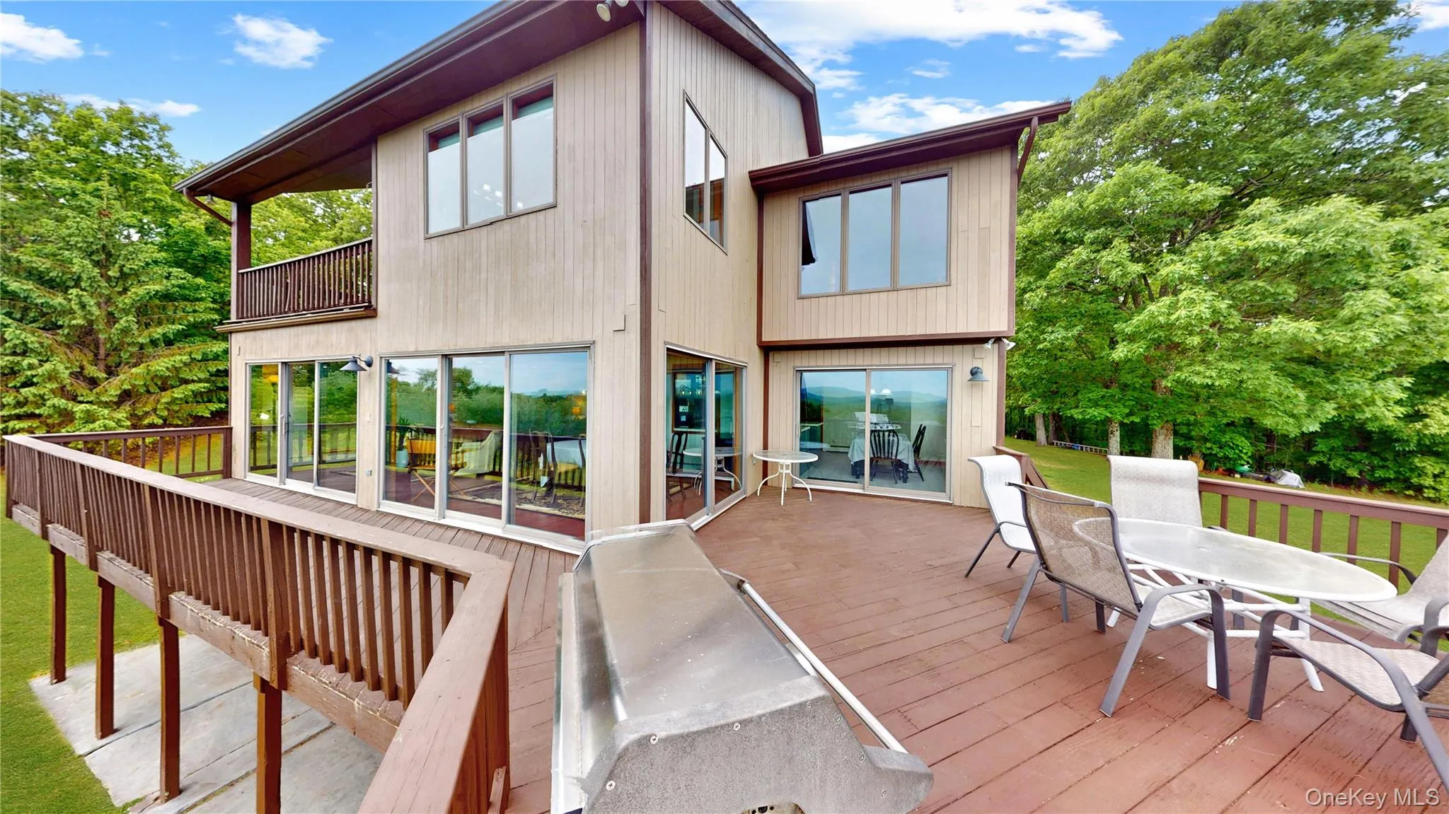 Expansive wood-finish deck with perimeter railing and outdoor wall-mounted lighting Expansive wood-finish deck with perimeter railing and outdoor wall-mounted lighting