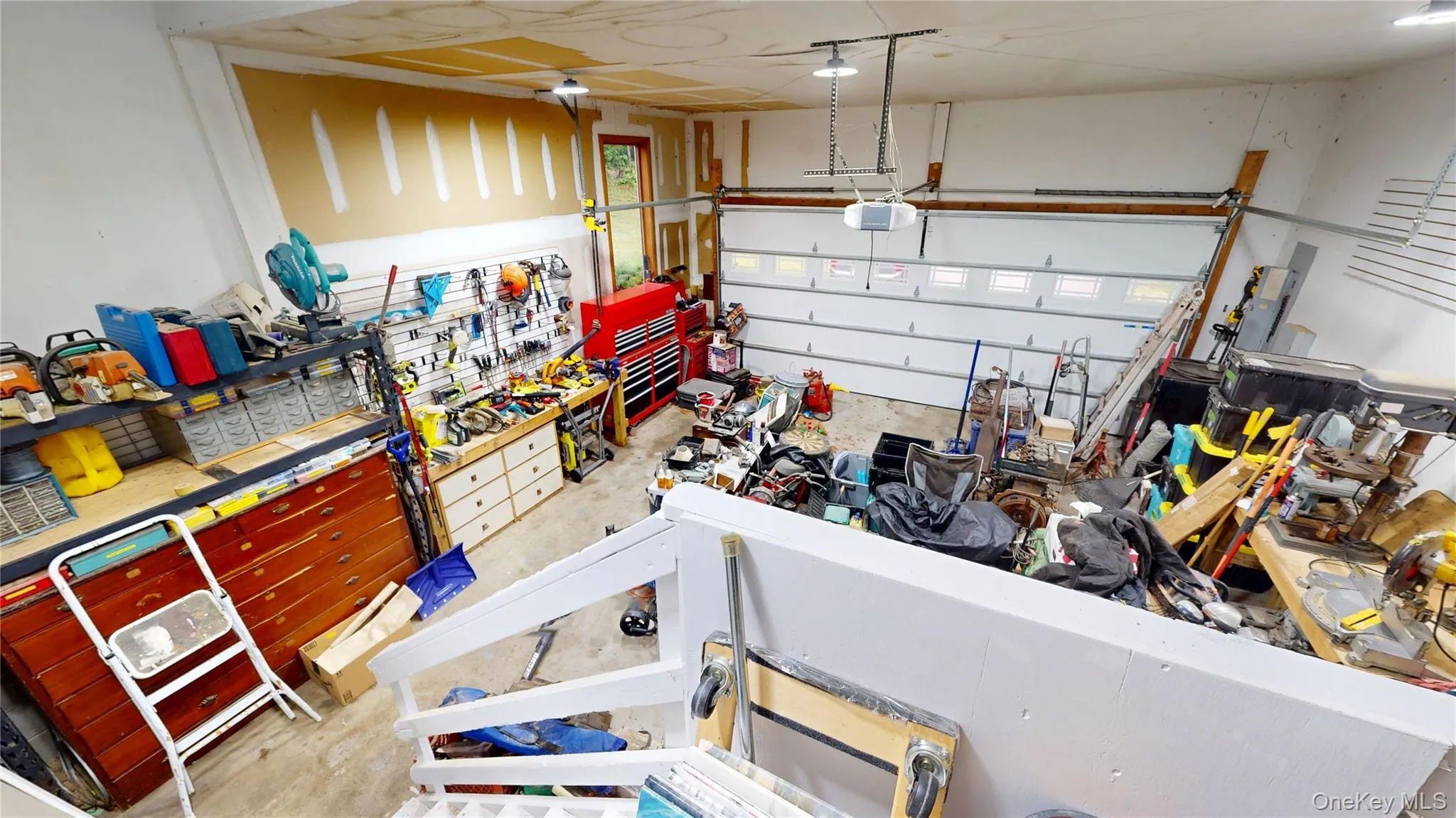 Spacious garage featuring a sectional overhead door, exposed ceiling joists, built-in shelving, and workbench space Spacious garage featuring a sectional overhead door, exposed ceiling joists, built-in shelving, and workbench space