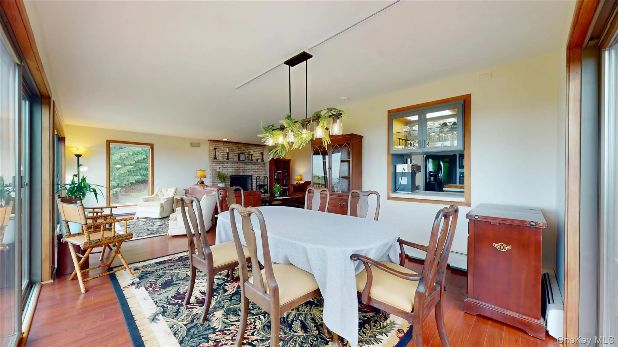 Dining area featuring wood-finish flooring, a contemporary linear chandelier, and a built-in display cabinet with glass doors Dining area featuring wood-finish flooring, a contemporary linear chandelier, and a built-in display cabinet with glass doors