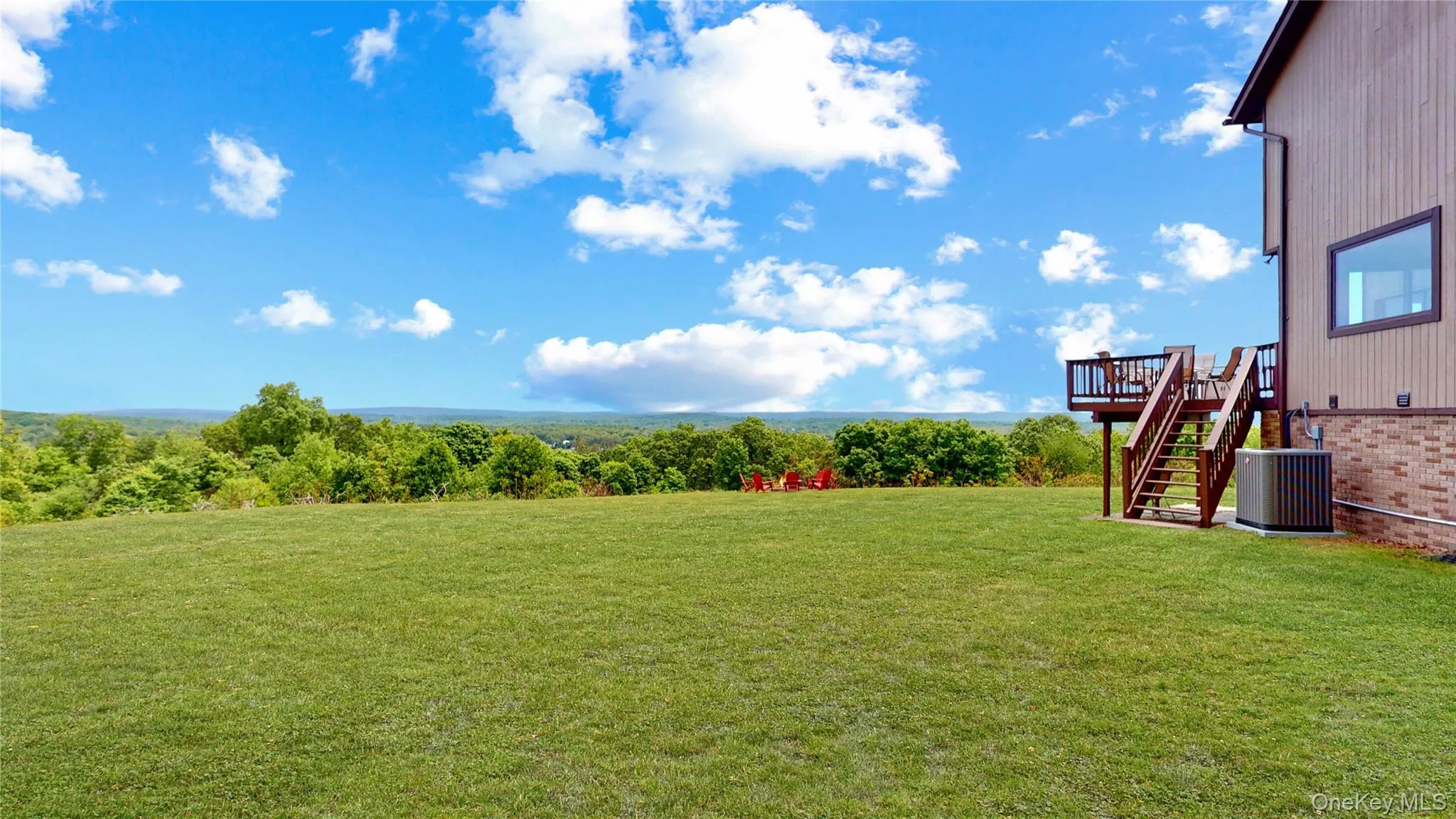 Expansive green lawn with a multi-level deck featuring wood railings and stairs Expansive green lawn with a multi-level deck featuring wood railings and stairs