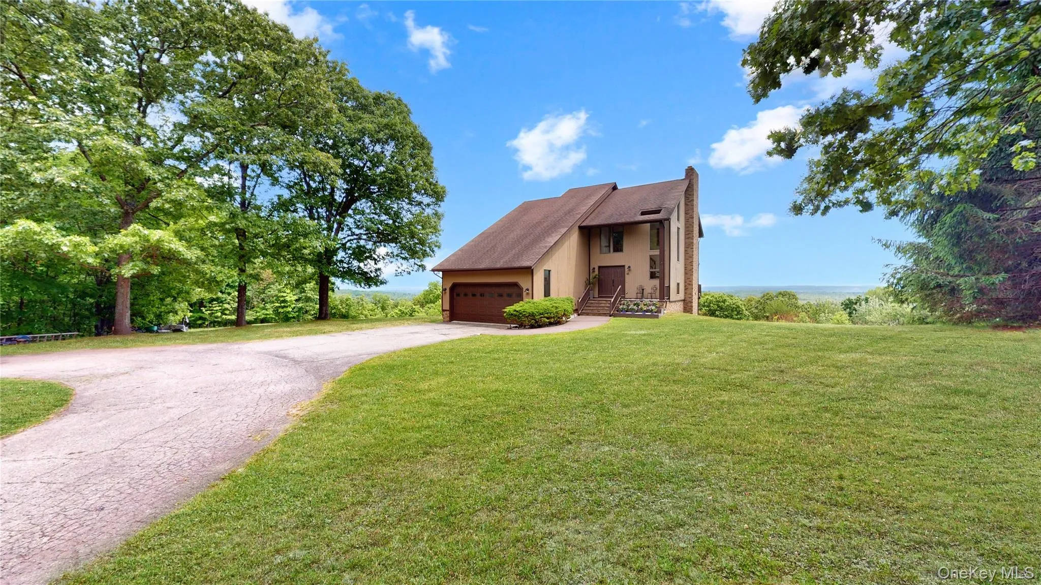 Contemporary-style residence featuring a two-car garage, mature trees, and a spacious front lawn Contemporary-style residence featuring a two-car garage, mature trees, and a spacious front lawn