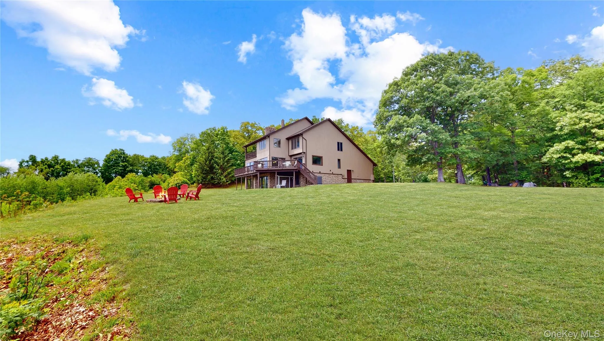 Expansive verdant lawn with a multi-level deck and surrounding mature trees Expansive verdant lawn with a multi-level deck and surrounding mature trees