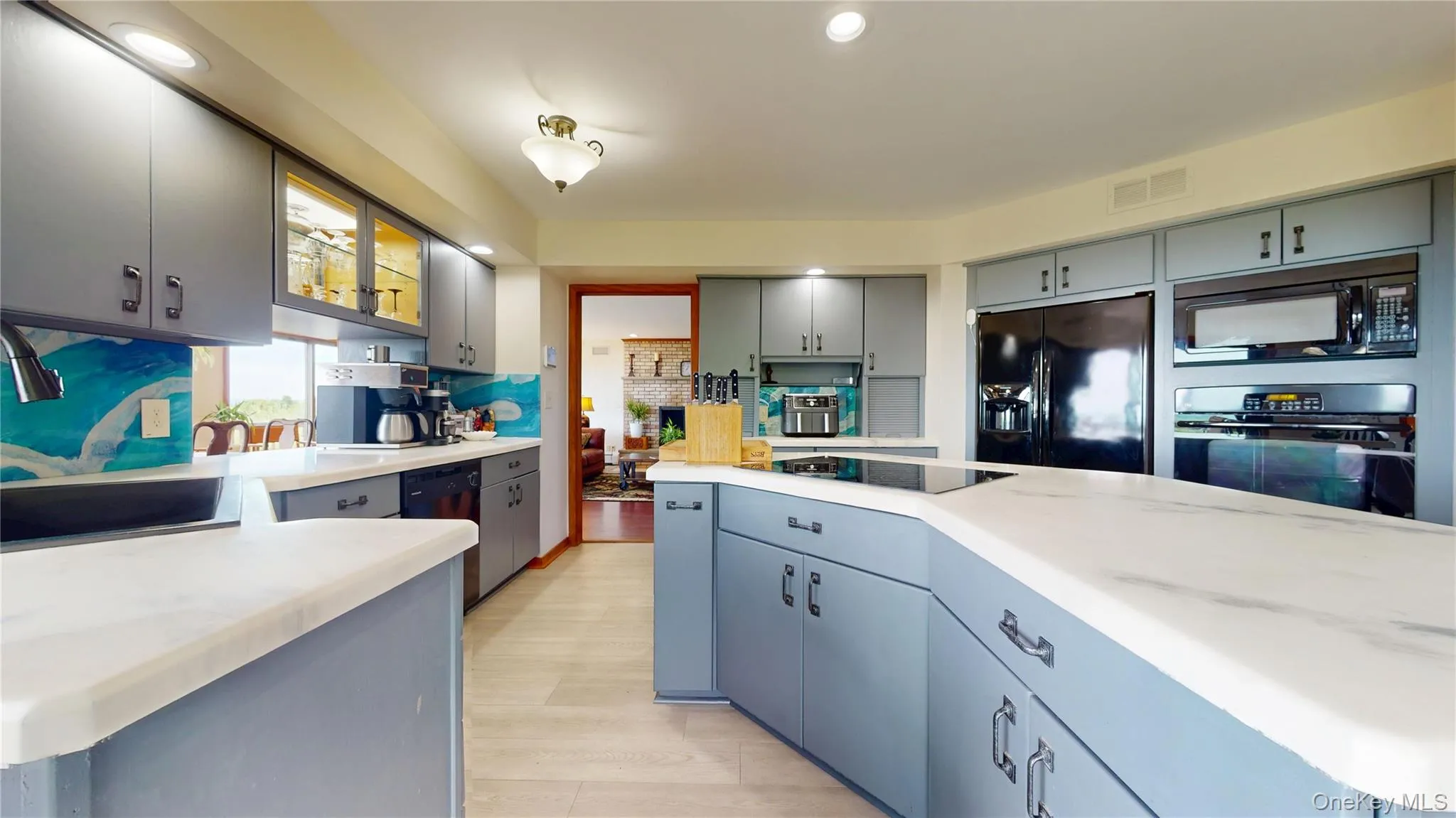Spacious kitchen featuring an expansive island, light-toned flooring, modern gray cabinetry, integrated appliances, and recessed lighting Spacious kitchen featuring an expansive island, light-toned flooring, modern gray cabinetry, integrated appliances, and recessed lighting
