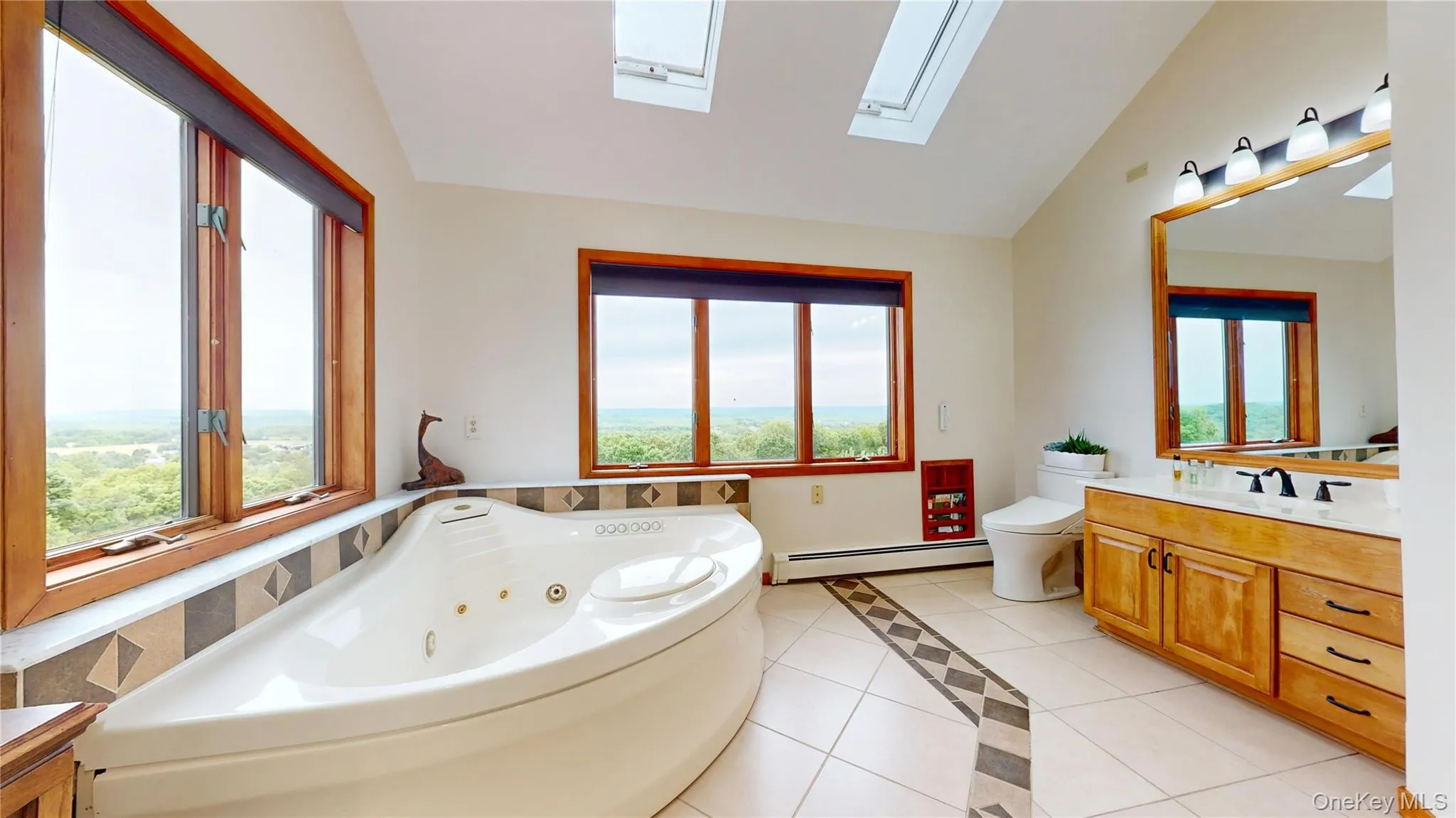 Spacious bathroom featuring a white corner jetted tub, skylights, and multiple windows with wood trim Spacious bathroom featuring a white corner jetted tub, skylights, and multiple windows with wood trim