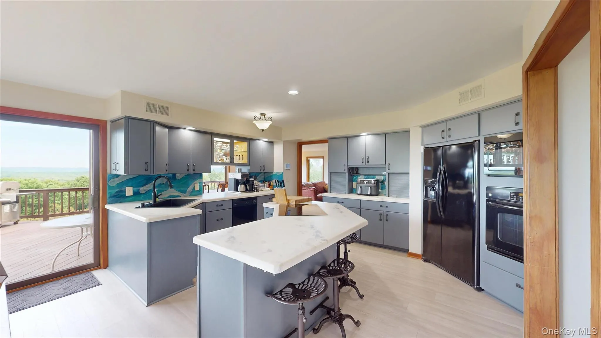 Modern kitchen featuring light gray cabinetry, white countertops, and a vibrant blue wave-patterned backsplash Modern kitchen featuring light gray cabinetry, white countertops, and a vibrant blue wave-patterned backsplash